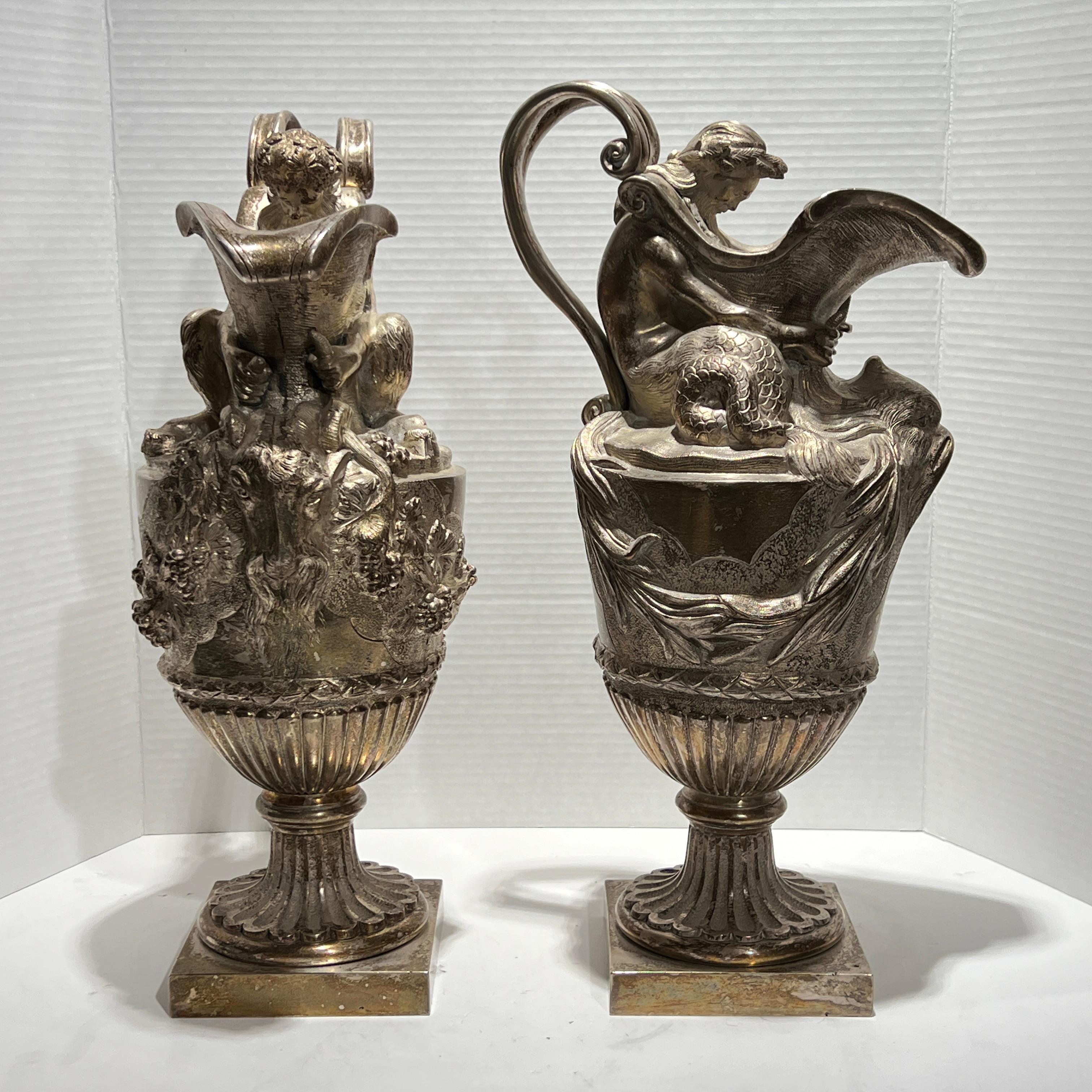 Pair of antique (19th century) French silvered bronze ewers in the French Louis XVI style, after the original designs by Sigisbert-Francois Michel (1728-1811). One with the figure of a triton with dolphin mask and rushes, and the other with a  satyr