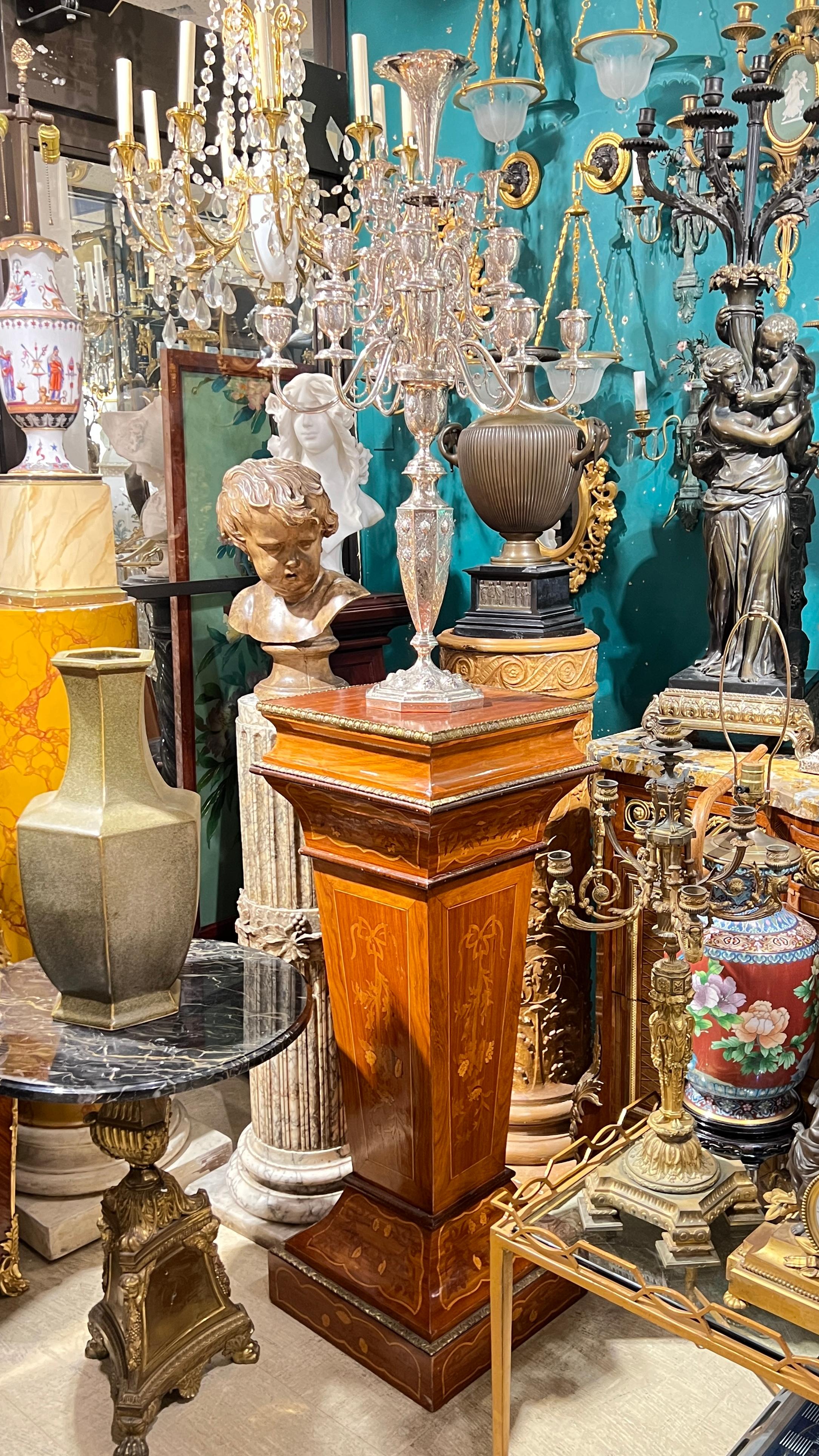 Splendida coppia di piedistalli antichi (XIX secolo) realizzati in legno di frutta con deliziosi disegni intarsiati di fogliame e nastri con decorazioni in bronzo dorato ai bordi dei piani e della base.