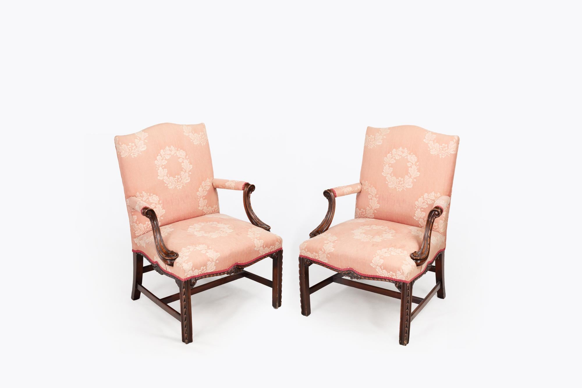 Pair 19th Century Gainsborough Library Chairs, the shaped backs over padded arms with scrolled and reeded curved supports and carved apron details adorn the fronts and sides. The pair are raised above carved decorative front legs and joined by a