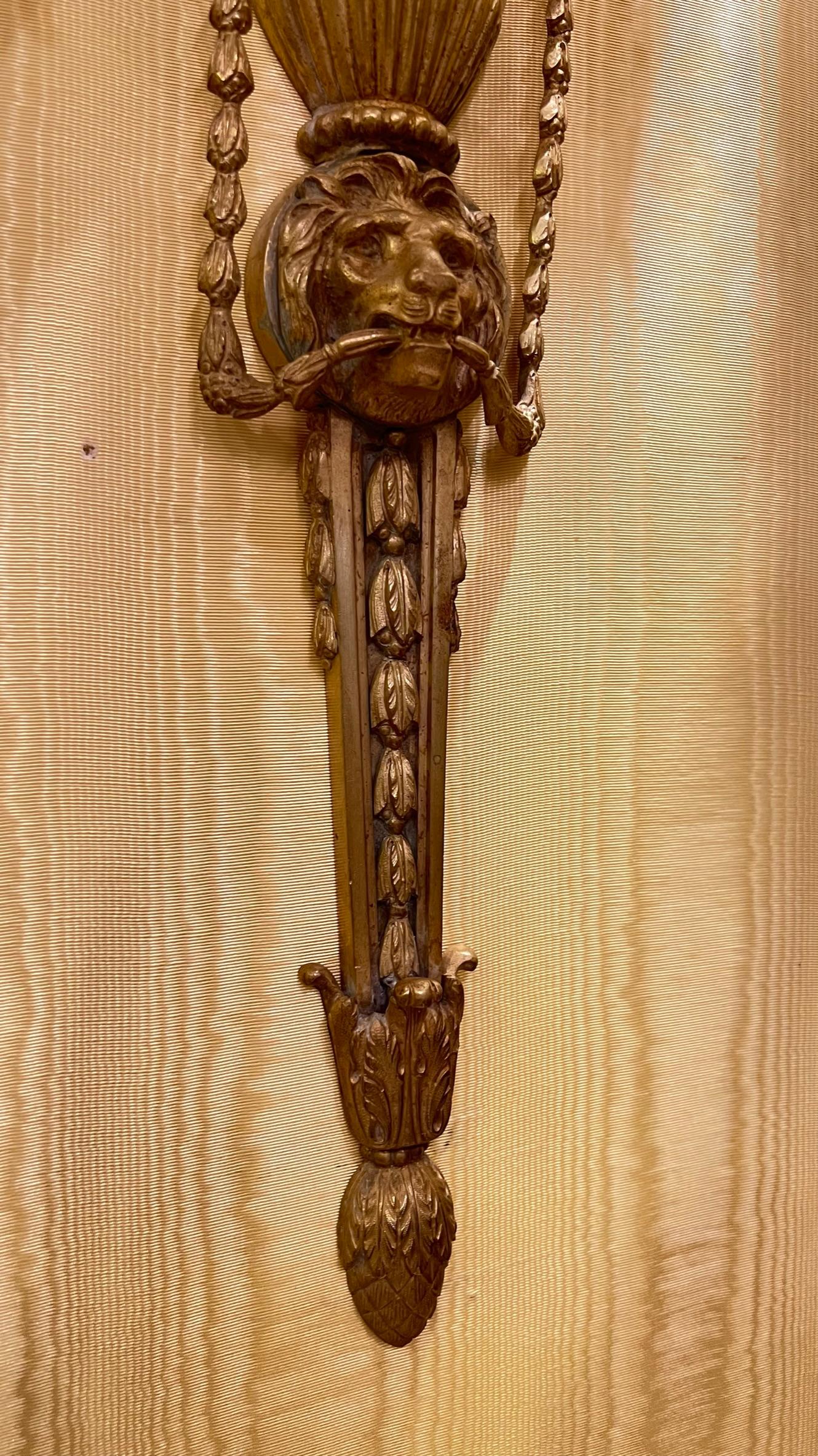 Paire de lampes de poche françaises du 19e siècle  Appliques en bronze doré avec des motifs néoclassiques comprenant une urne, des clochettes, des masques de chèvre et de lion, et trois bras de bougie.  S'accorde particulièrement bien avec un décor