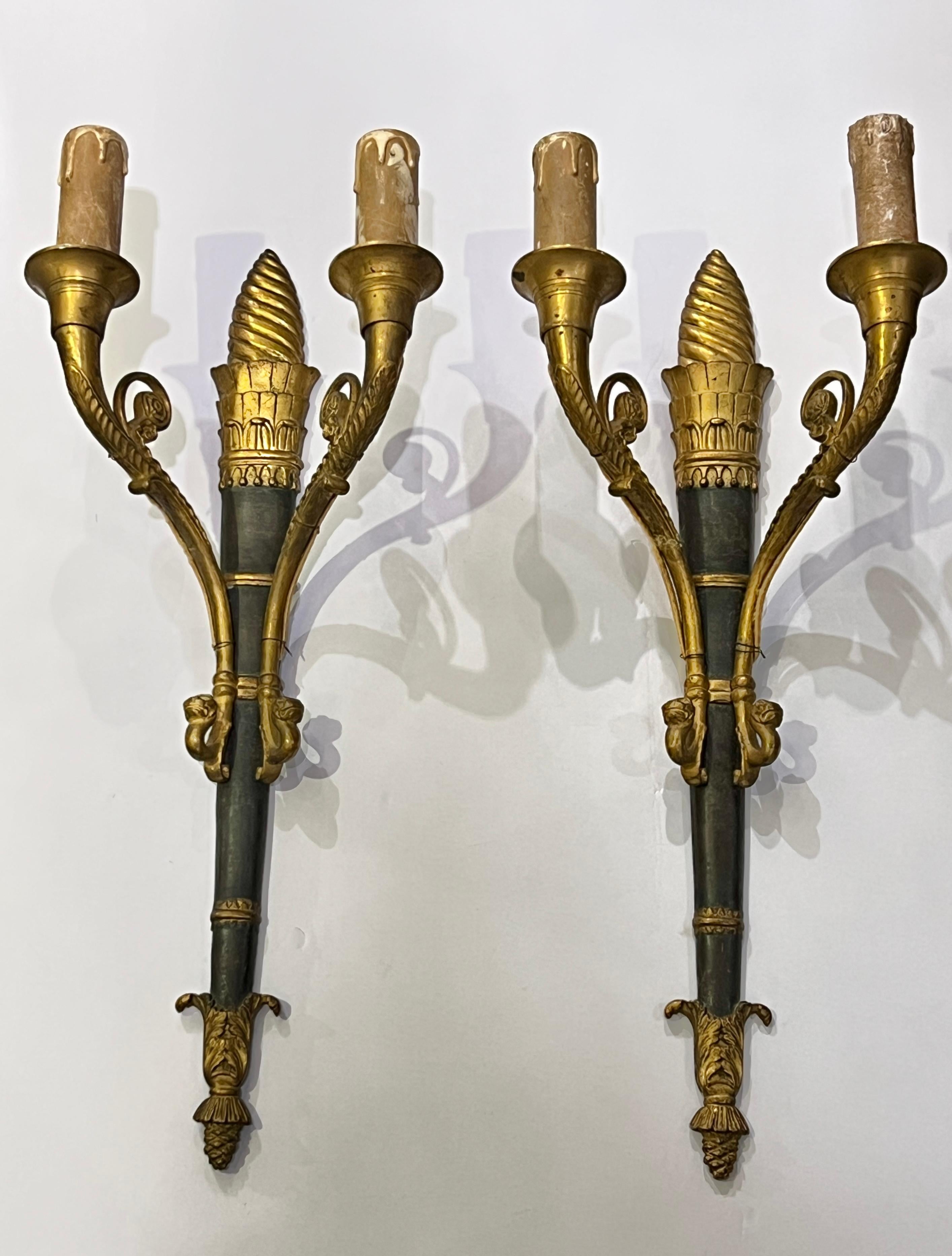 Paire d'appliques anciennes (19e siècle) de style Empire français, en forme de torche enflammée, avec des surfaces patinées et dorées et deux bras de bougie électrifiés avec des douilles d'origine de la taille d'un candélabre et un câblage ancien.