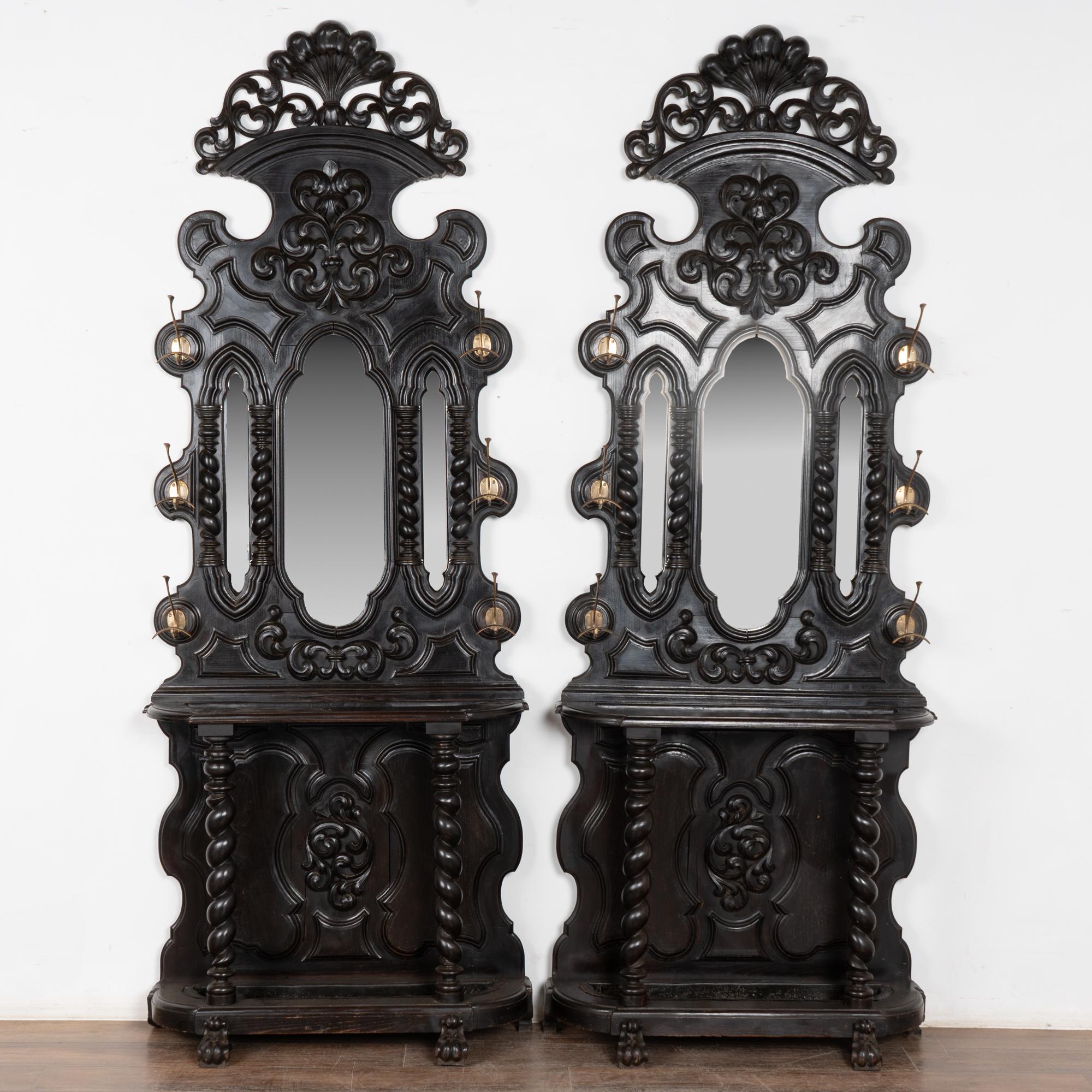 Paire de consoles d'entrée spectaculaires avec sculptures décoratives, trois miroirs et six porte-manteaux ou porte-chapeaux sur chacune d'elles, toutes deux mesurant plus de 8 pieds de haut. Chaque console dispose d'un cadre ouvert prêt à