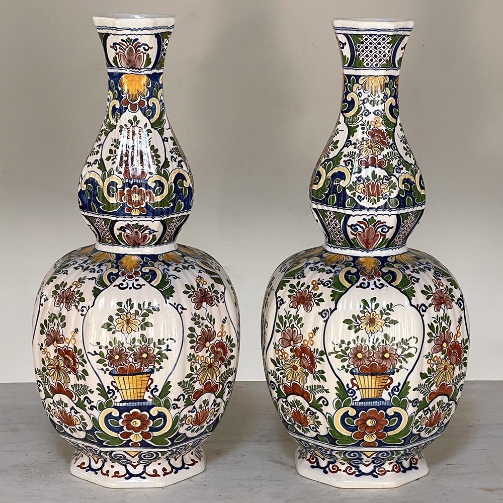 Pair 19th century hand-painted flower vases from Rouen are typical of the colorful and artistic works from the storied region, capturing the vivid natural hues of the region onto timeless classical forms. The faceted urns narrow to a waist above