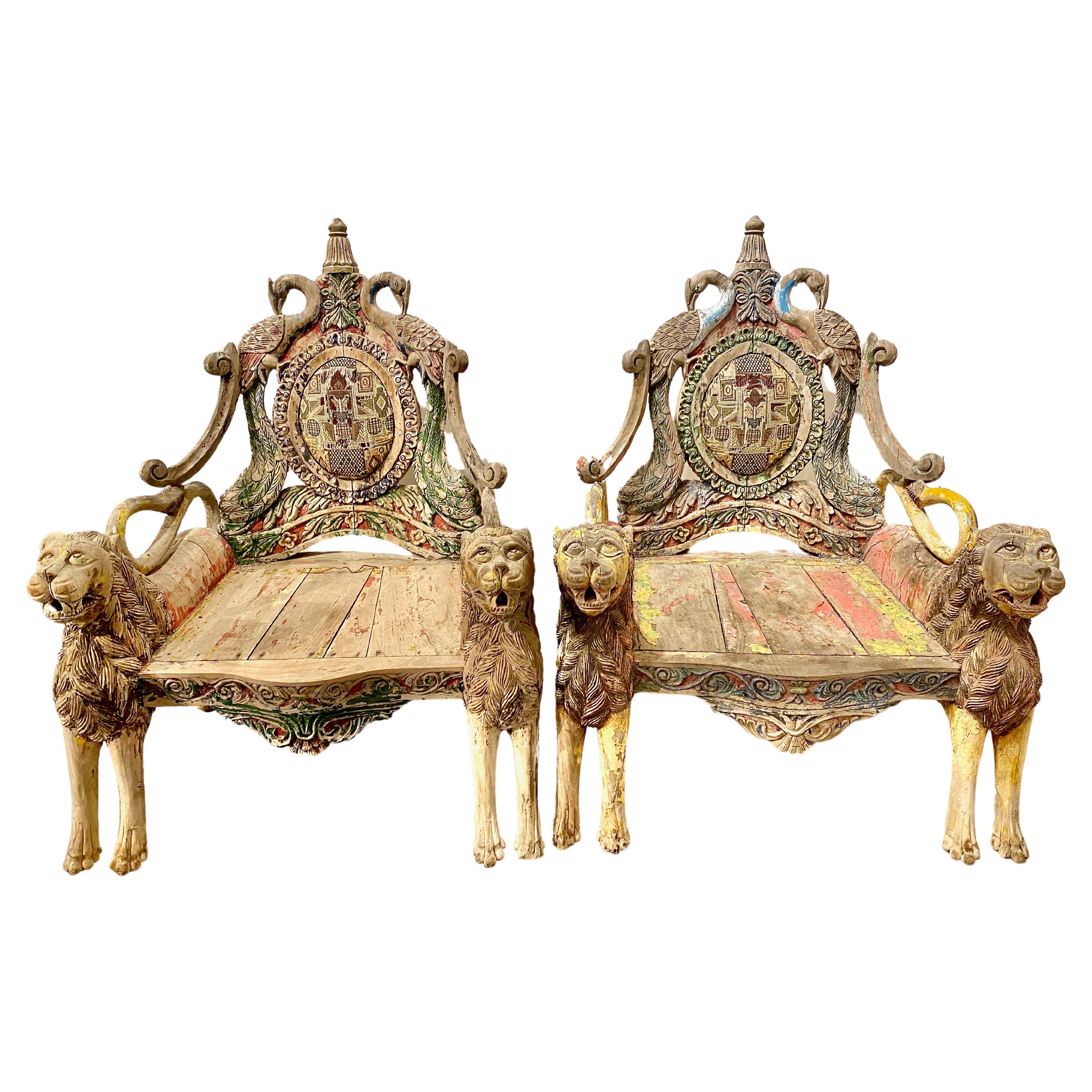 This is an extraordinary pair of Indian Throne or elaborate antique Ceremonial Chairs. The chairs are composed of pairs of fully carved lions supporting the wide seats whose backs incorporate carved peacocks surmounted by crowns. The scrolling lion