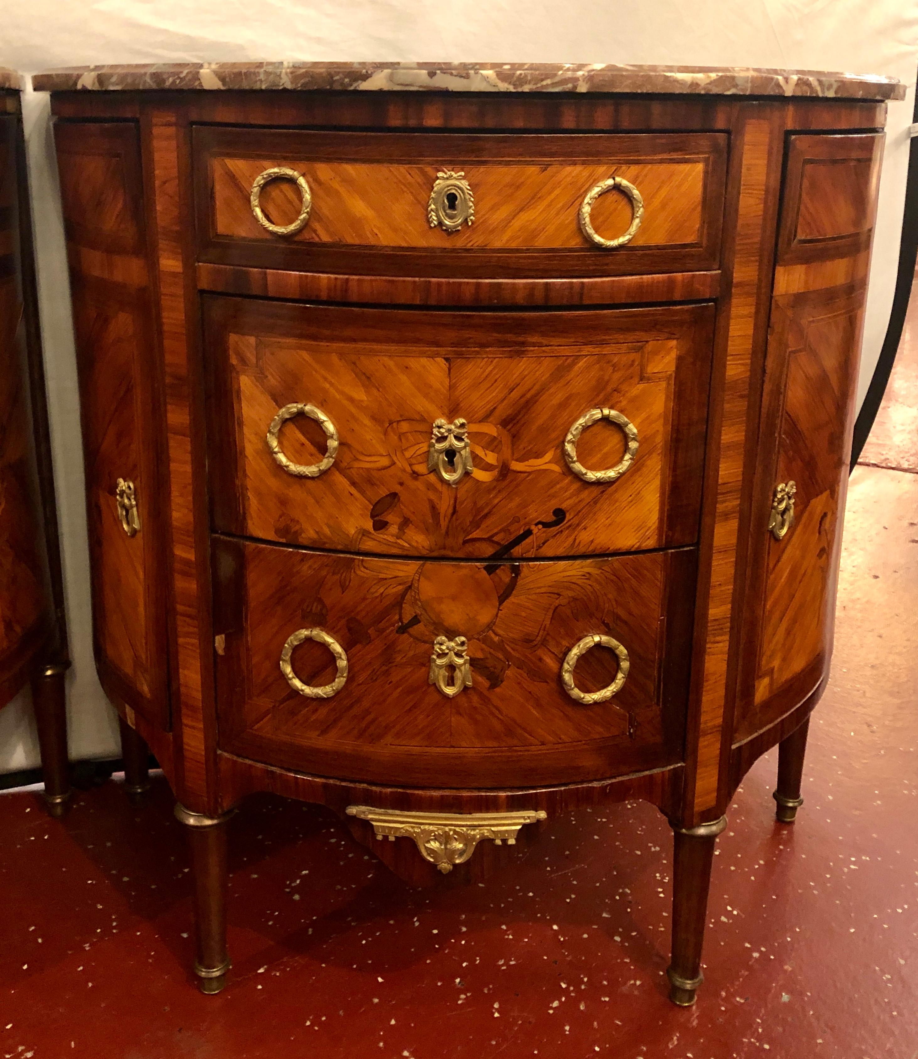 Pair of 19th century inlaid French marble top demilune commodes or nightstands. Each of these fine cabinets have musical theme inlaid in the wood with fine bronze mounts.