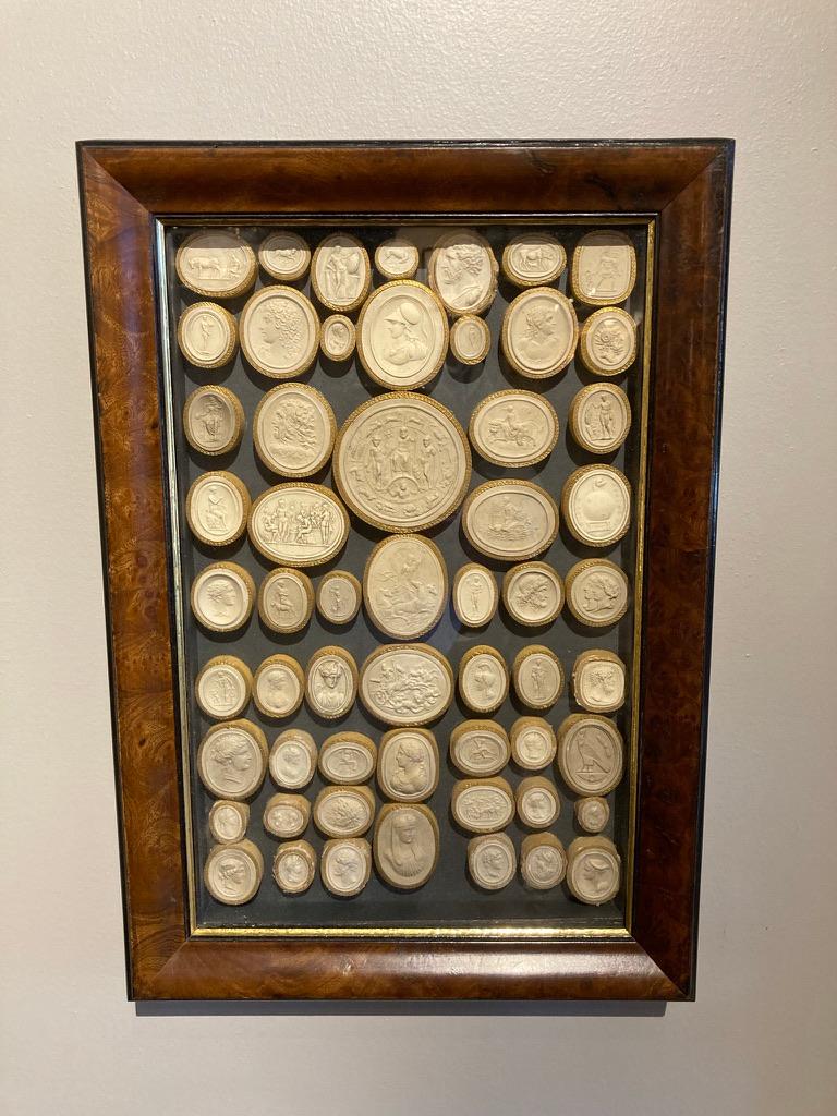 A pair of framed collections Grand Tour Italian plaster intaglios, early 19th century. These are very fine examples, with minute details, all wrapped in the original gilt edged paper and mounted in handsome burl wood frames with ebonized and gilt