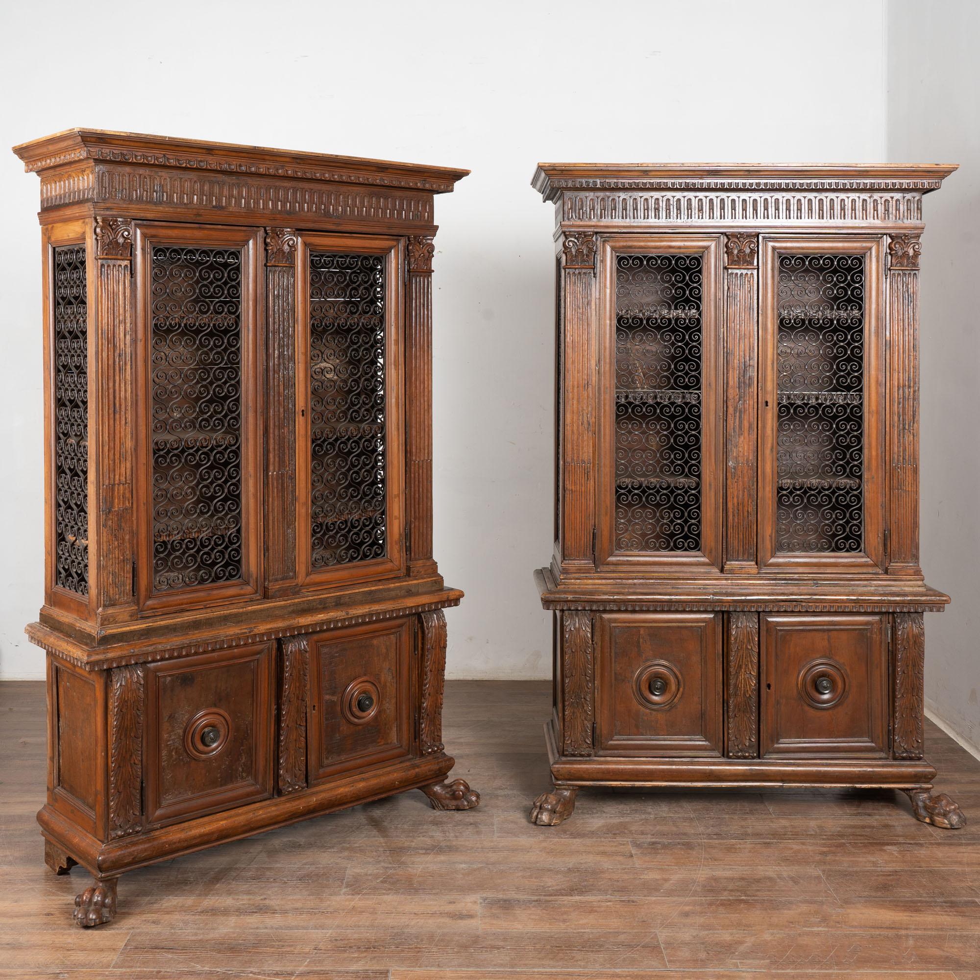Pair, Italian walnut cabinets with metal grillwork upper doors and fixed interior shelving.
Note the extensive carving, including egg and dart details along crown and shelves, acanthus leaves, and large lion's paw feet.
Restored, strong/stable. Old