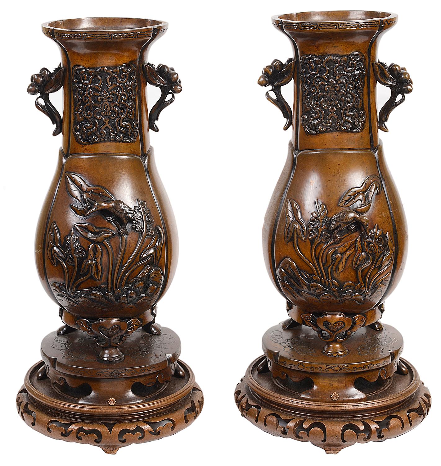 Ein Paar japanischer Bronzevasen guter Qualität aus dem 19. Jahrhundert mit Ständern, jeweils mit erhabenem Blumen- und Vogelrelief, montiert auf Ständern aus Bronze und geschnitztem Holz.