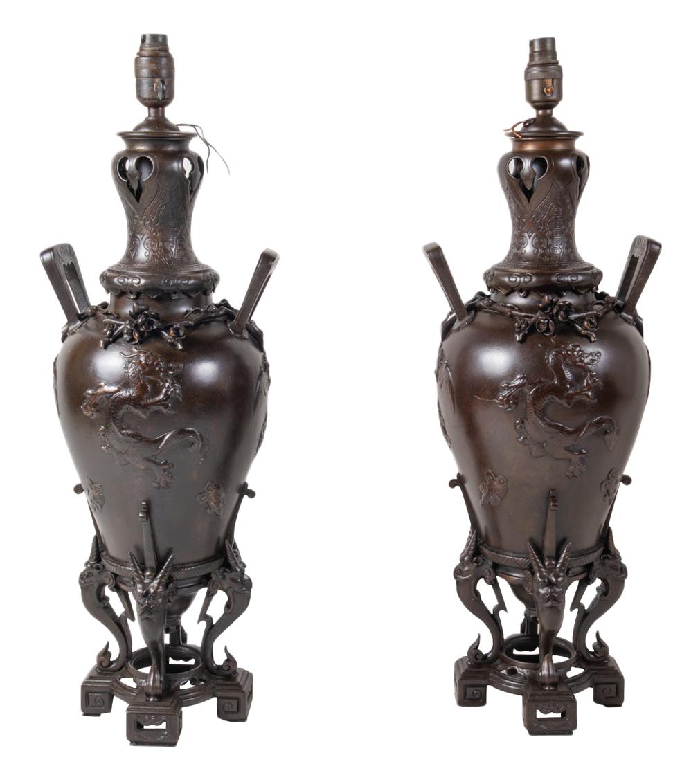 A fine quality pair of 19th century French patinated bronze vases / lamps in the Japanese style. Each with two handles on either side, embossed flower and bat decoration, supported by three mythical horned creatures.