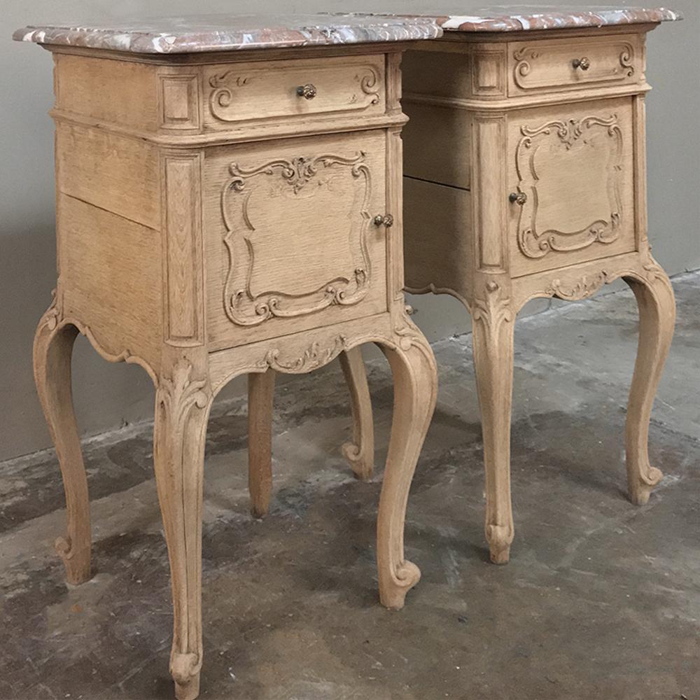 Pair of 19th century Liegoise stripped oak marble top nightstands were rendered from solid oak by the master artisans of Liege, and include four scrolled legs with carved embellishment supporting the surprisingly spacious cabinets above, each with a