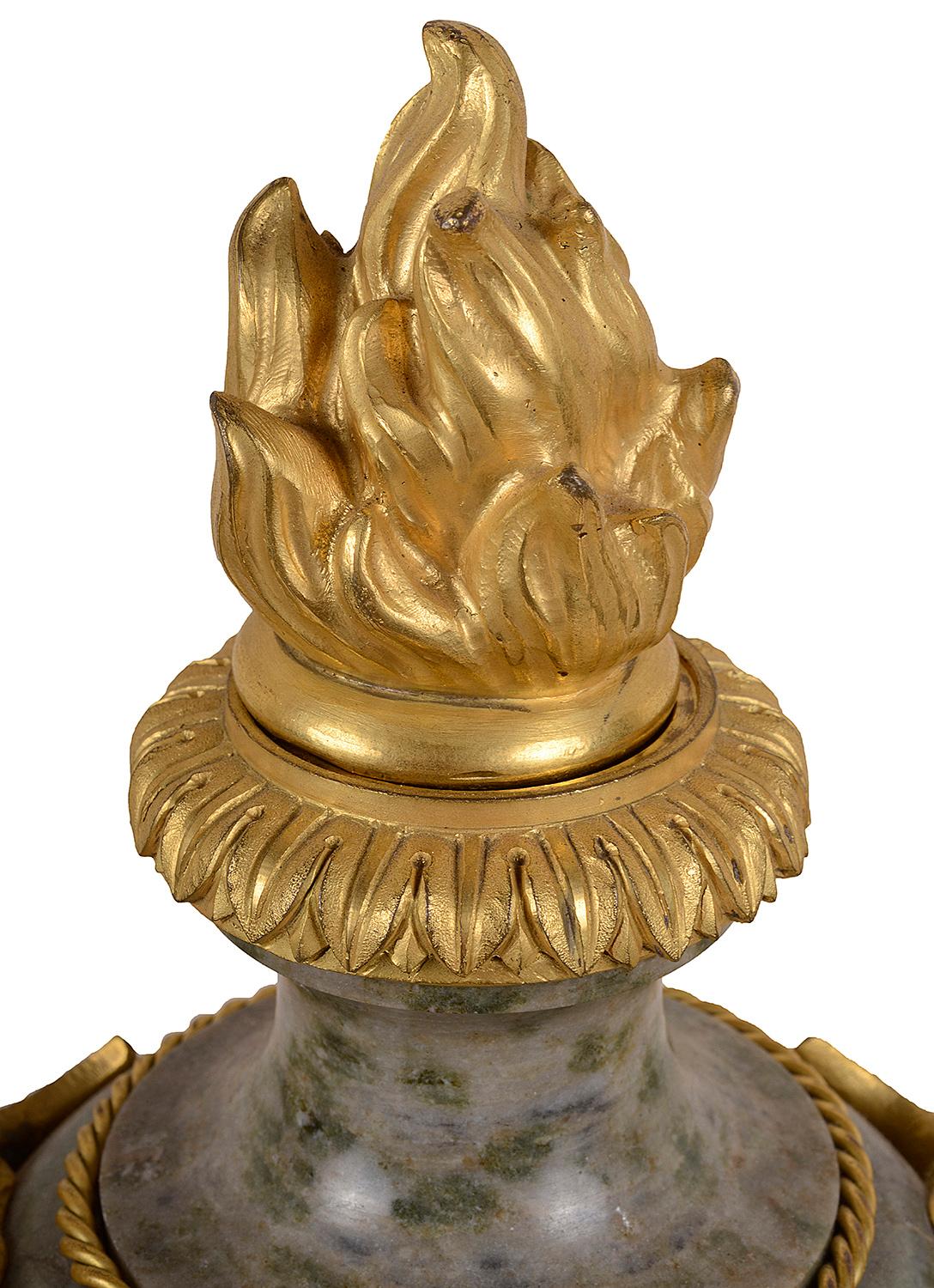 Paire de vases classiques français du XIXe siècle en marbre gris de bonne qualité, avec des finales à flamme en bronze doré et des montures en forme de masques mythiques.
