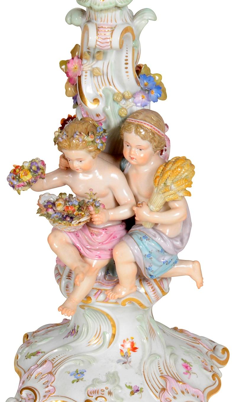A very good quality pair of 19th century German Meissen porcelain three branch candelabra, each with two children representing 'Summer' and 'Fall' holding the harvest and grapes.
Blue crossed swords to the base of both.