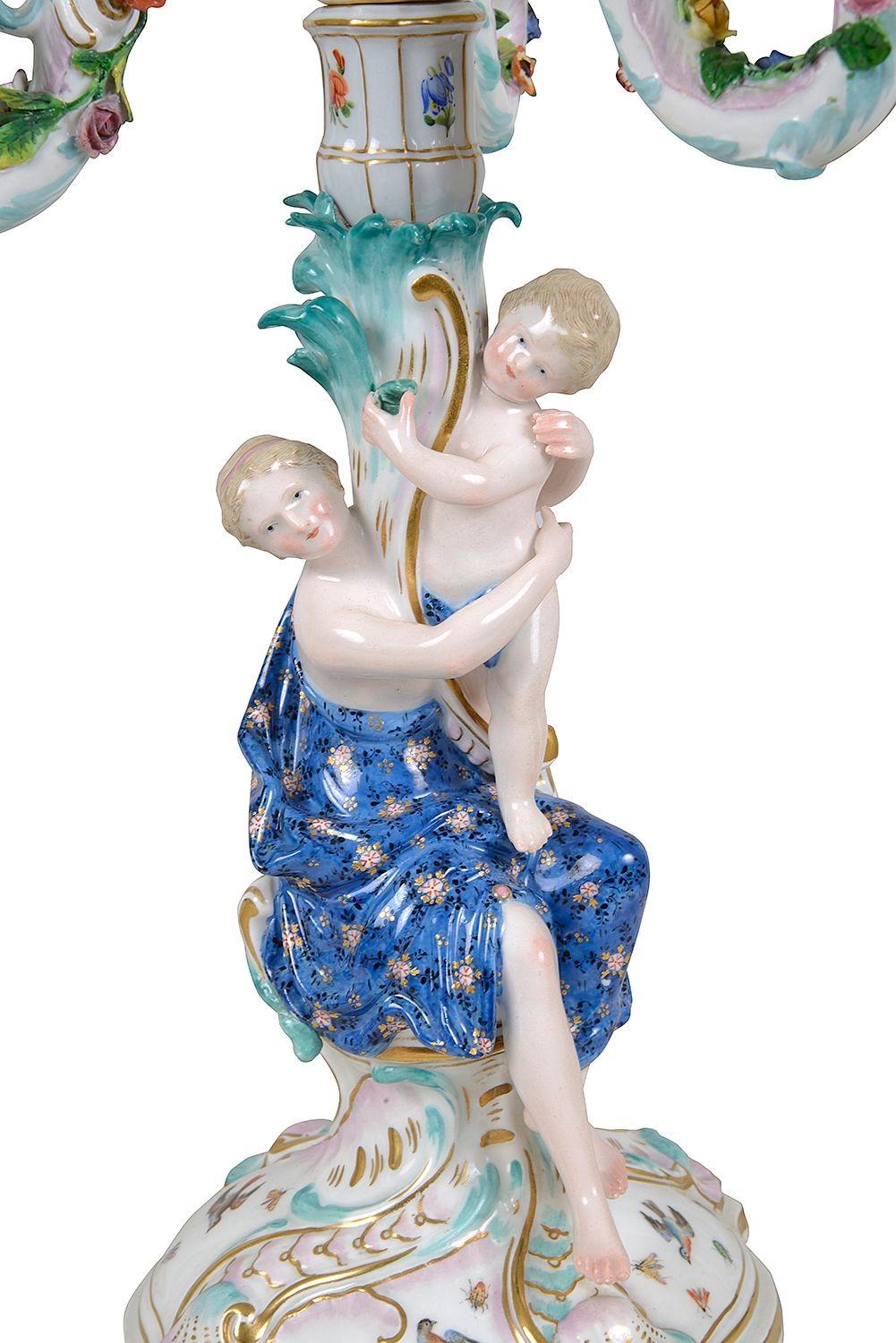 Coppia di candelabri a tre rami in porcellana Meissen Porcelain del XIX secolo, di ottima qualità. Ciascuna di esse presenta figure femminili classiche che tengono in braccio un bambino, con decorazioni a volute sui bracci e sollevate su basi a