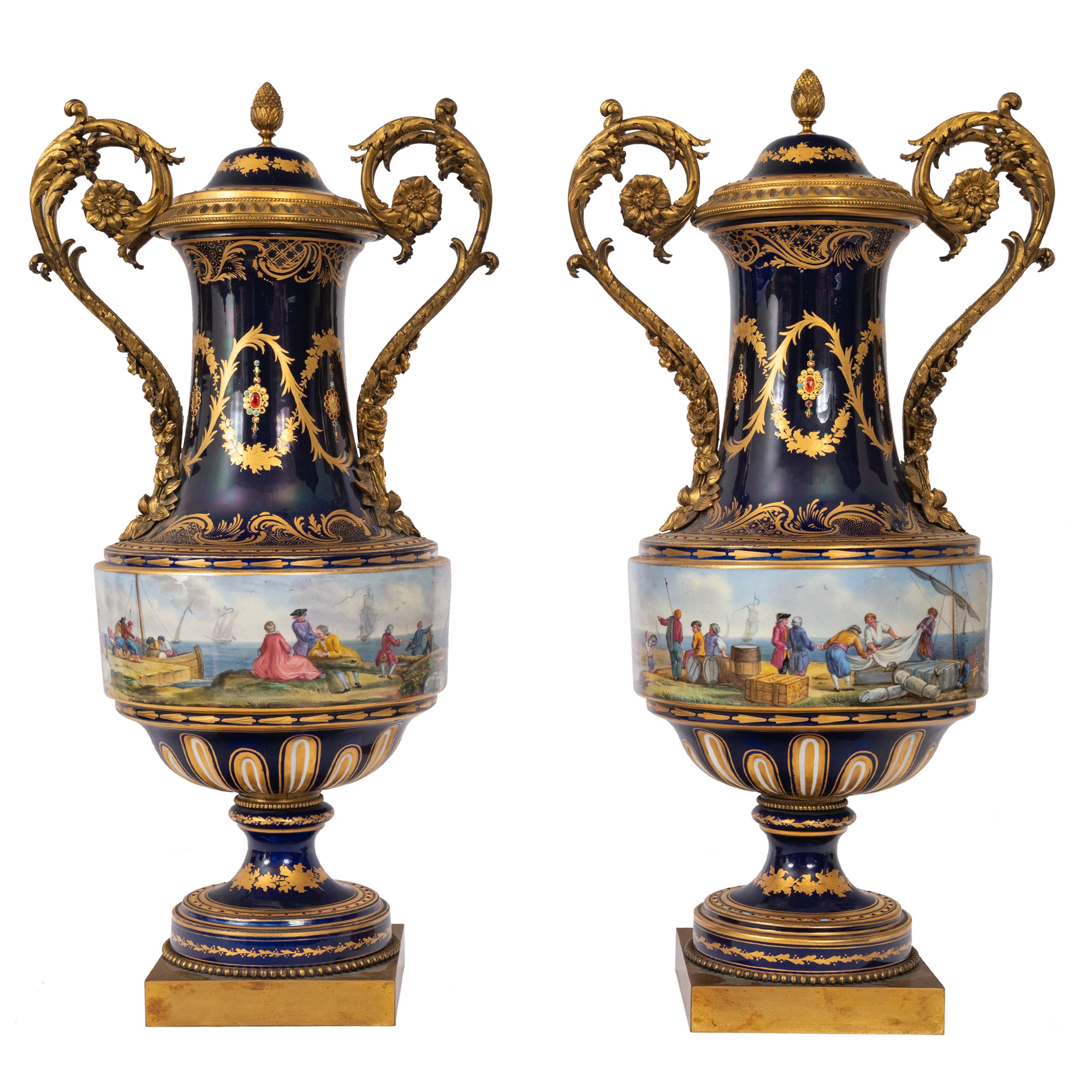 Une paire exceptionnelle et monumentale d'urnes à couvercle en porcelaine de style Sèvres peinte à la main et en bronze doré, vers 1860.
Chaque urne présente un fond bleu cobalt et un couvercle bombé surmonté d'un fleuron en forme d'ananas en