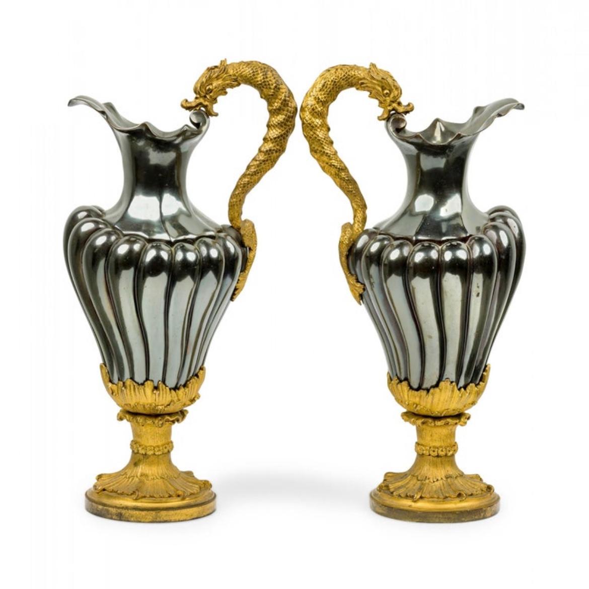 Paire d'aiguières (pichets) anciennes (19e siècle) en bronze doré décoratif français, se distinguant par leur patine émaillée noir/charbon irisé, avec des poignées en forme de dragon et des décorations de feuillage sous-marin.  Non signée.