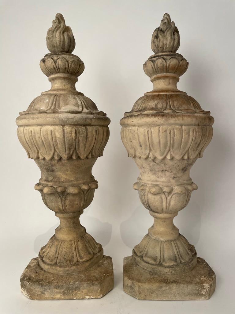 Pair of Italian neoclassical style urns in relief that can either stand on their own or hang from the wall as decorative elements. Quite handsome, with acanthus leaf decoration and flame finials, modeled after ancient Roman originals. Something that
