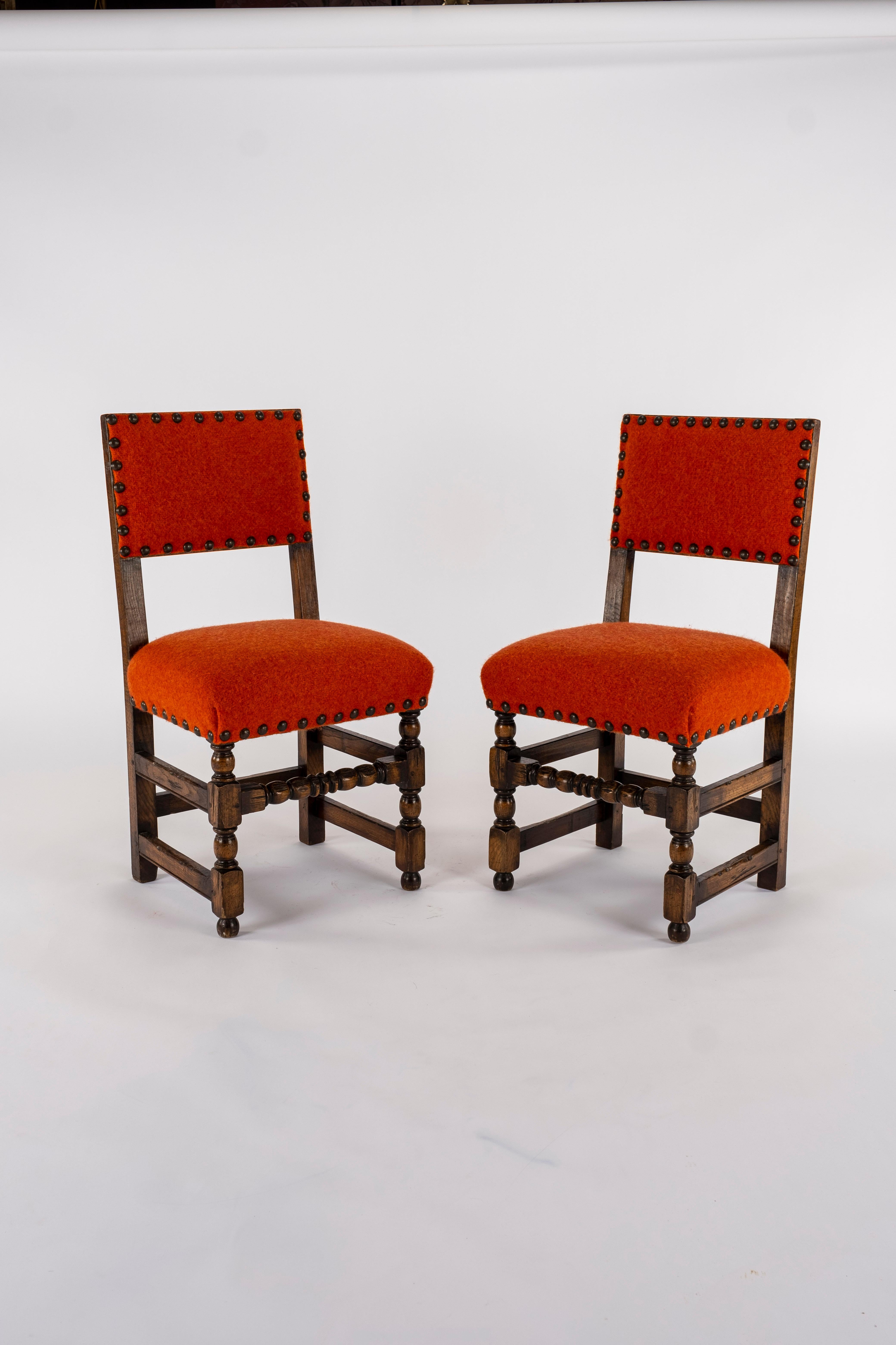 Handsome French Louis XIII style walnut chairs newly upholstered in a heavy felted orange red wool with nailhead detail.