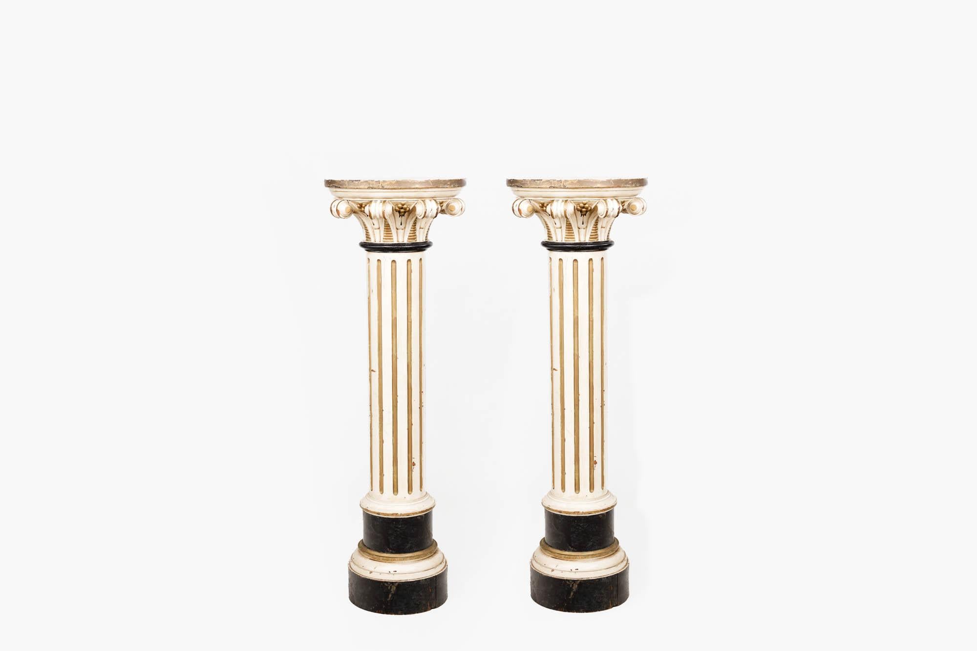 Pair 19th century painted pine Corinthian column pedestals in the classical Italian style with scrolling acanthus leaves and fluted detailing. The pair are finished in an off-white paint with parcel gilt highlights.