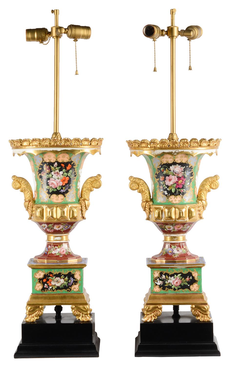 A very stylish pair of late 19th century Paris porcelain hand painted urns on stands converted to lamps. Each with wonderful inset painted panels of flowers, gilded Ormolu and porcelain mounts and handles, raised on plinth bases and ebonized bases.