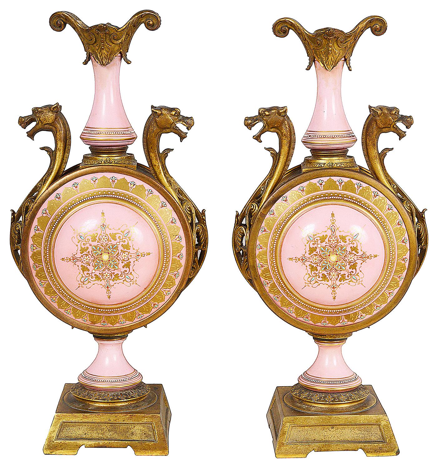 Ein sehr dekoratives Paar rosa Porzellanvasen mit zwei Henkeln im französischen Sèvres-Stil des 19. Jahrhunderts, jeweils mit vergoldeten Ormolu-Fassungen und handgemalten Szenen von liegenden Jungfrauen mit spielenden Putten.