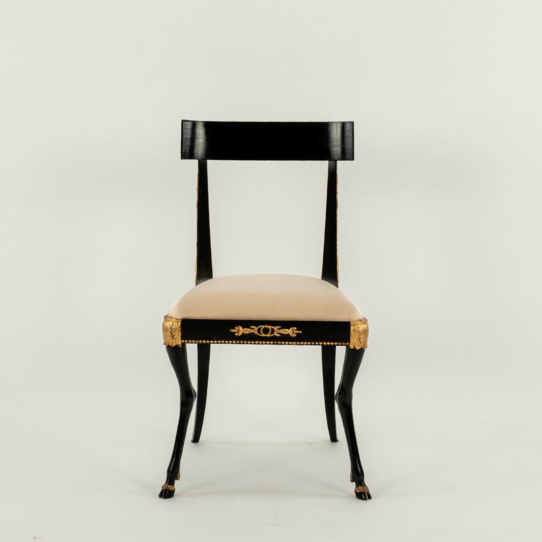Paar Regency Klismos-Stühle aus dem 19. Jahrhundert. Diese eleganten Stühle haben einen Rahmen aus ebonisiertem Hartholz, klassische vergoldete Details, geschnitzte Pied-de-Biche und neu gepolsterte Sitze aus cremefarbenem Seidensatin.