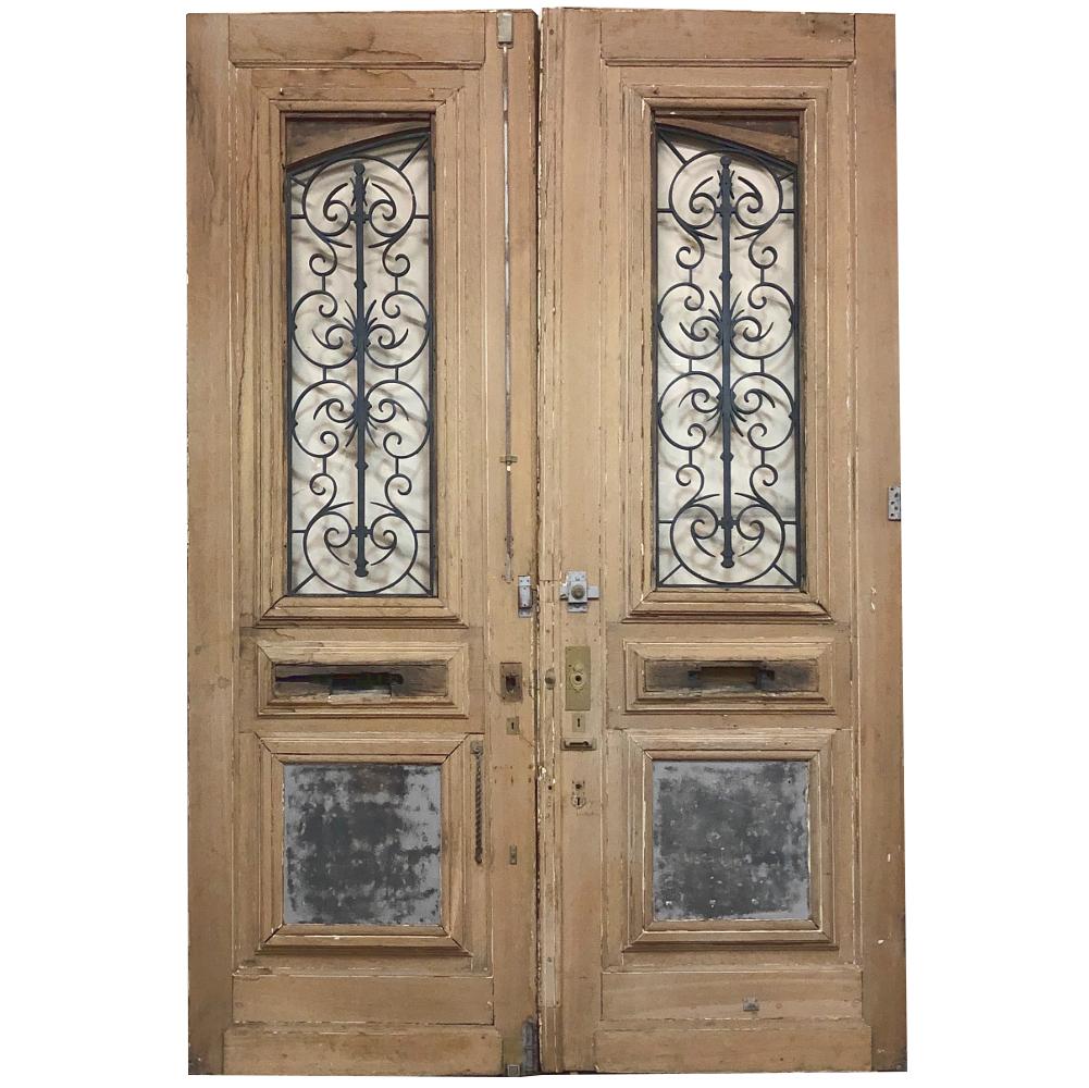 Pair of 19th century solid oak doors with wrought iron inserts are a masterwork of architectural detail that are destined to provide a magnificent entryway for your home! Measuring a full eleven feet tall, each massive door is over two inches thick