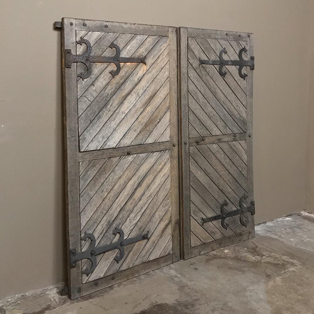 Pair 19th century solid oak shutters with forged iron hinges are a decorative way to cover windows, or use as accents in their own right! Diagonally oriented planks ensured maximum strength to withstand the fiercest storm! Use as a decorative