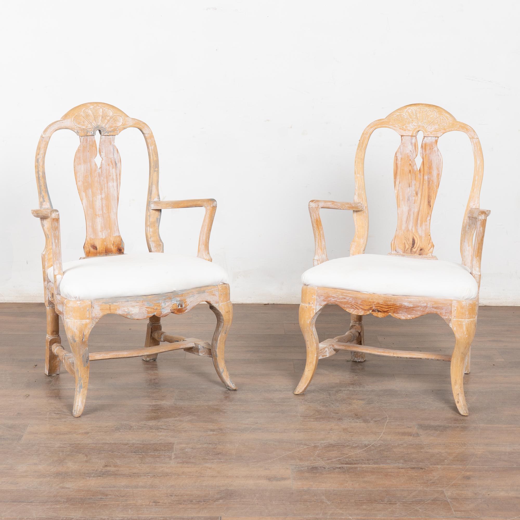 This graceful pair of Swedish Gustavian arm chairs have a wonderfully warm patina thanks to the soft, scraped finish revealing much of the natural pine wood below.
Note the residual white and even gray paint that brings an element of depth and