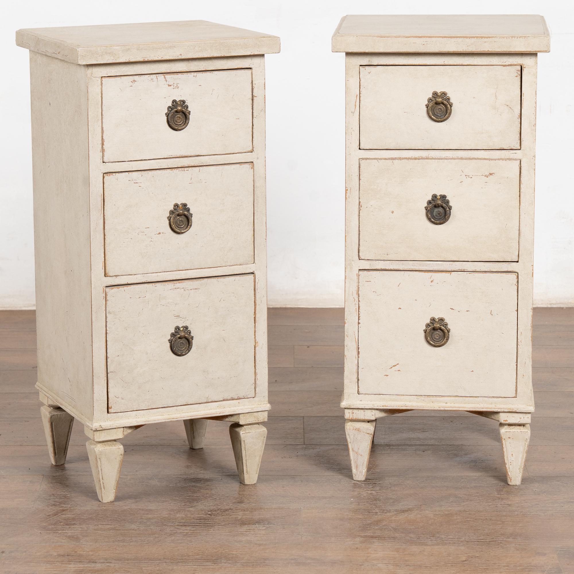 Coppia di cassettiere strette in pino in stile gustaviano con piedi affusolati, perfette per essere utilizzate come comodini o tavolini. 
I tre cassetti sono dotati di una ghiera in ottone per l'apertura.
La nuova finitura verniciata