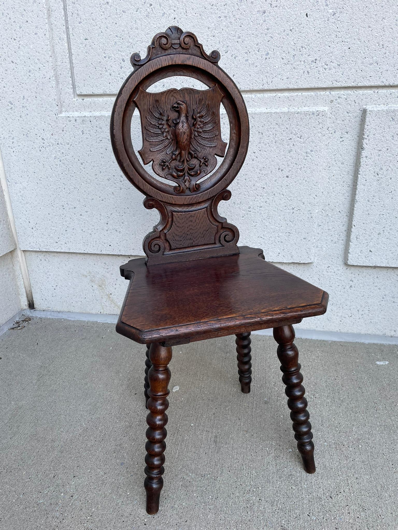 Handsome pair of Swiss oak side or hall chairs with circular open work backs holding a shield with beautifully carved eagles in the centers. In the alpine style with bobbin turned splayed legs. Deep and rich patina that only comes from age and use.