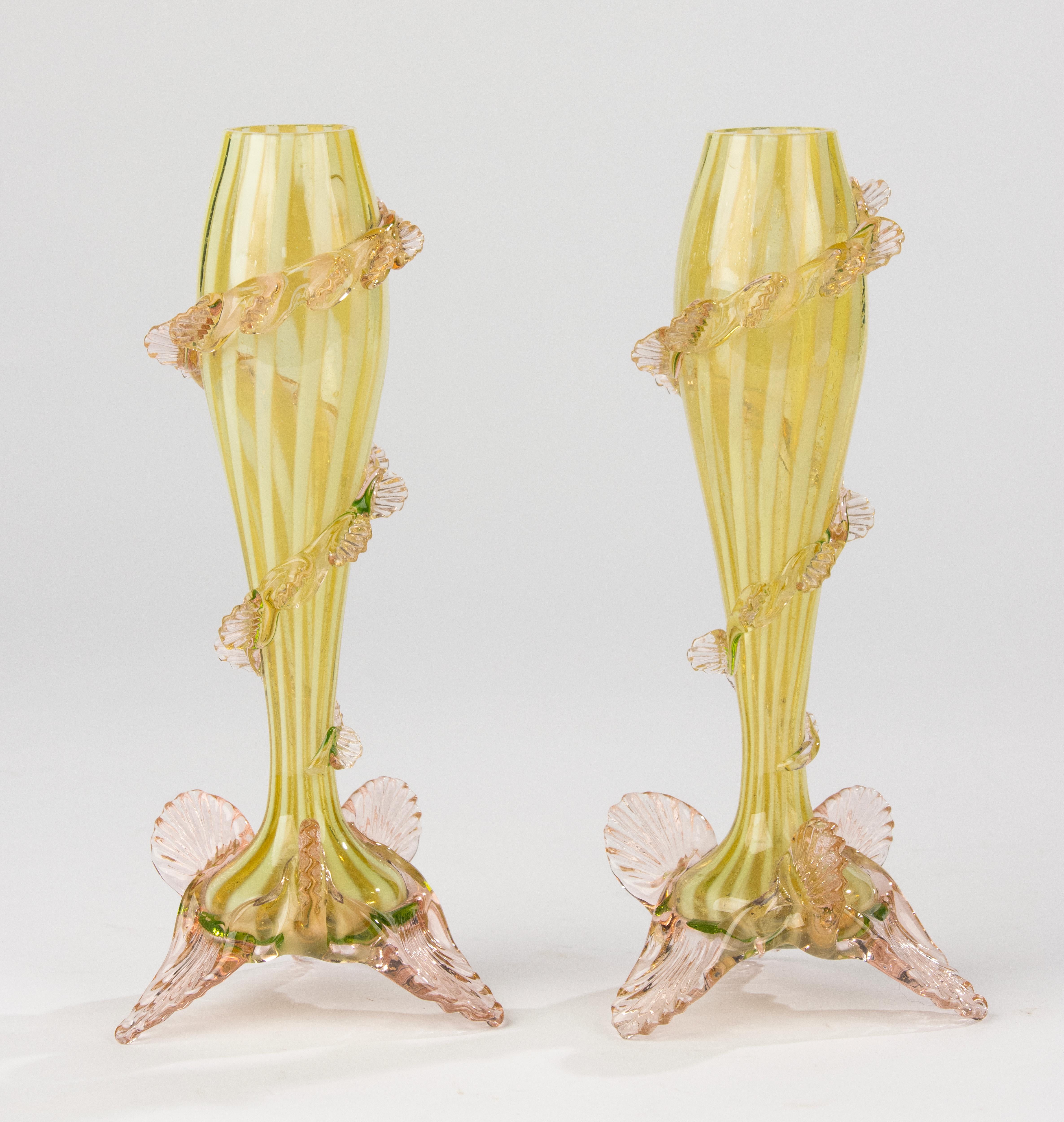 Beautiful pair of English Vaseline glass vases from the late 19th century. Each vase is hand-blown in a delicate yellow-green hue with soft pink accents on the base. The elegant spiral leaf design gracefully winds around the body, showcasing the