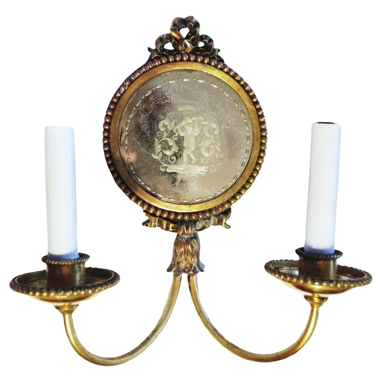 Pair c1890 Neoclassical style Bronze Wall Sconces Featuring Carved Back Eglomise Mirrored Wall Sconces. Signed by E.F. Caldwell. The cherubs are so sweetly rendered. One facing to the left and one facing front.