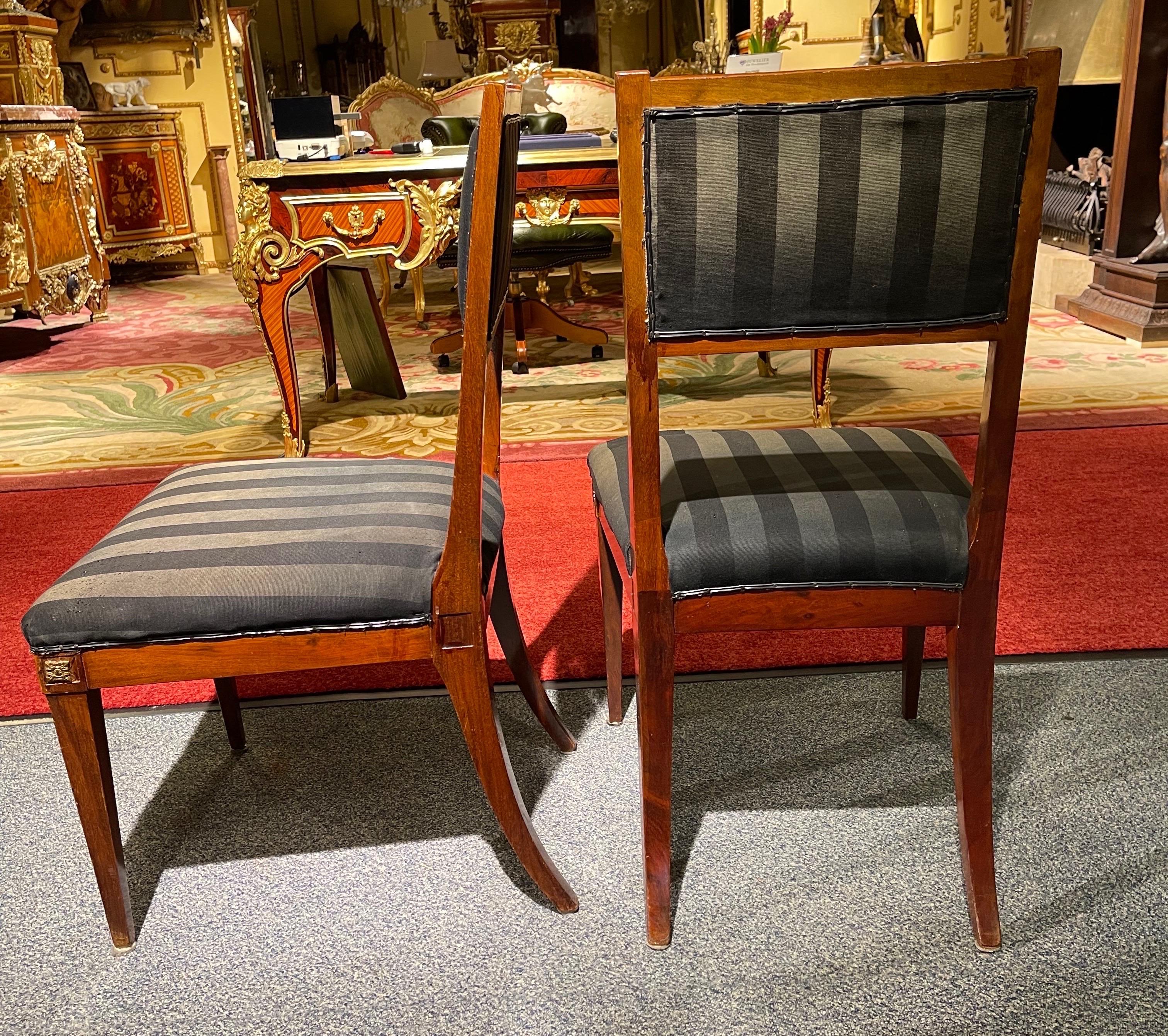 Pair (2) Empire chairs, around 1900

Solid wood mahogany. Upholstered seat and backrest covered with black fabric. Very stable and robust built. Hind legs in classic Empire saber shape. Timeless and classic design.