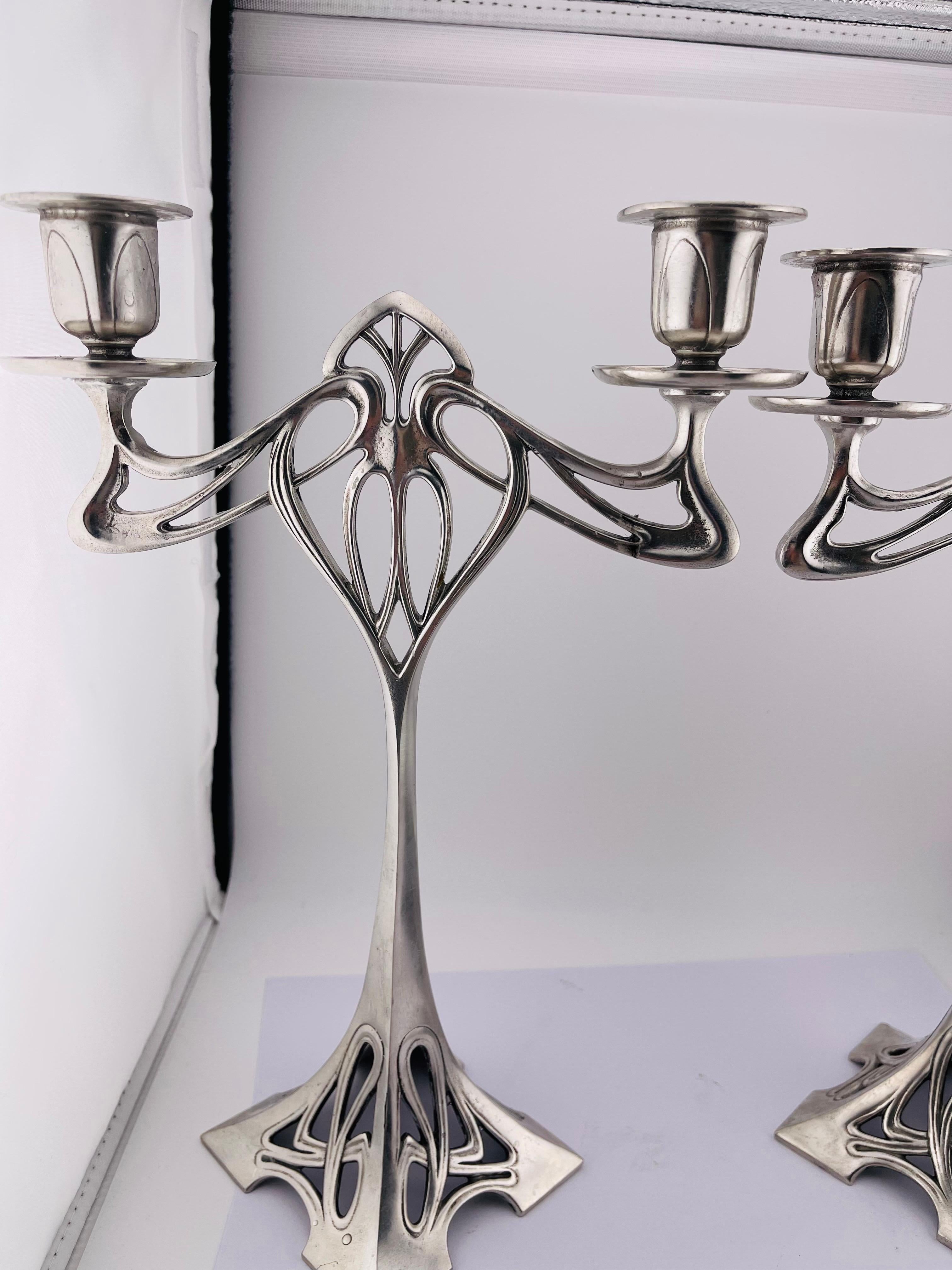 Coppia (2) imponenti candelabri Art Nouveau in peltro, placcati in argento


Questo elegante candeliere è un famoso capolavoro dell'Art Nouveau.
Tipico del design di quest'epoca era il forte mix di elementi geometrici e floreali e questo pezzo è