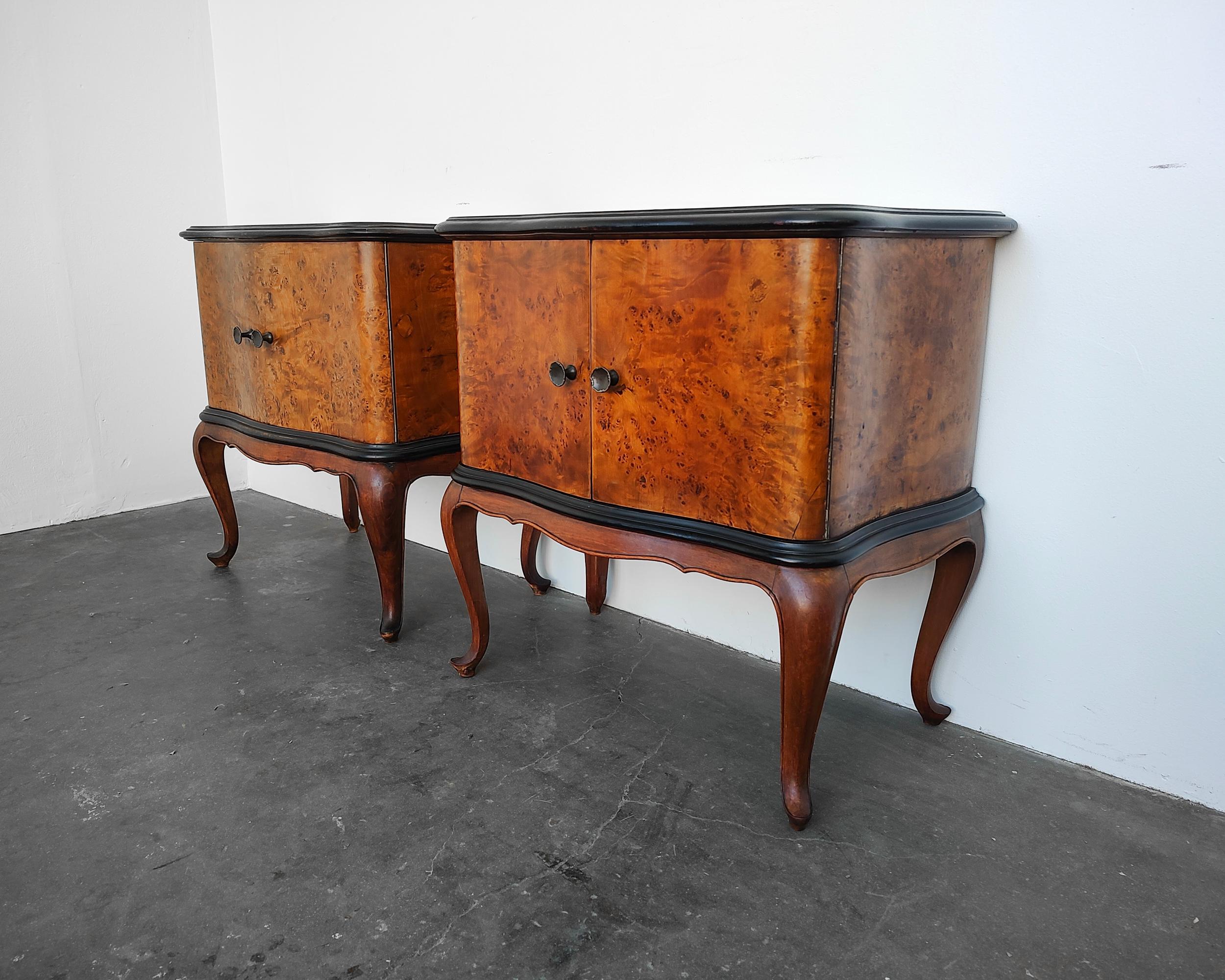 Set of two matching Queen Anne style burl bedside cabinets circa early 20th century.  Beautiful curved design details and contrasting black trim. Cabinet doors with brass knobs open to fixed shelf inside. Custom made protective glass sits on top.
