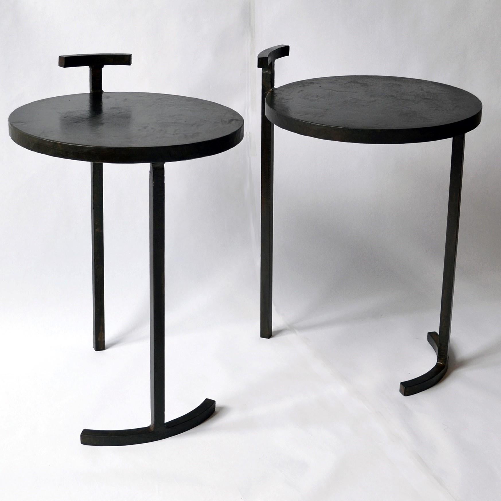 TABLE NO. 1 - PAIR 
J.M. Szymanski
d. 2017

This side table is made from cast, blackened, and waxed steel. This uniquely designed frame allows for a 1-inch thick, cast steel, circular top to balance on only two legs. This is the first table designed