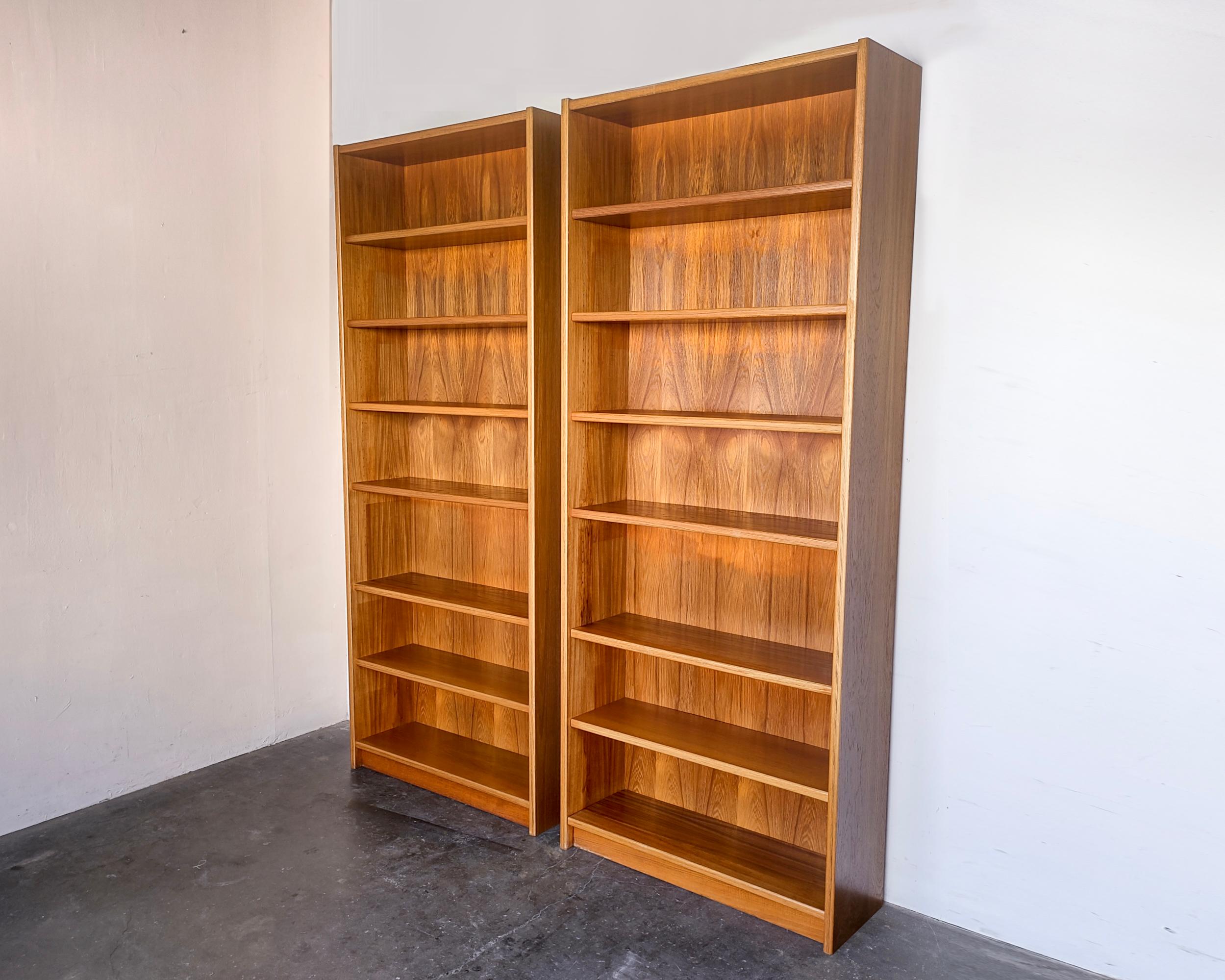 Set of two Danish modern teak bookshelves with six shelves on each. Adjustable shelves except one fixed in the center. Sun fading on interior surfaces and shelves, which would be made more apparent if the shelves are moved in different positions.