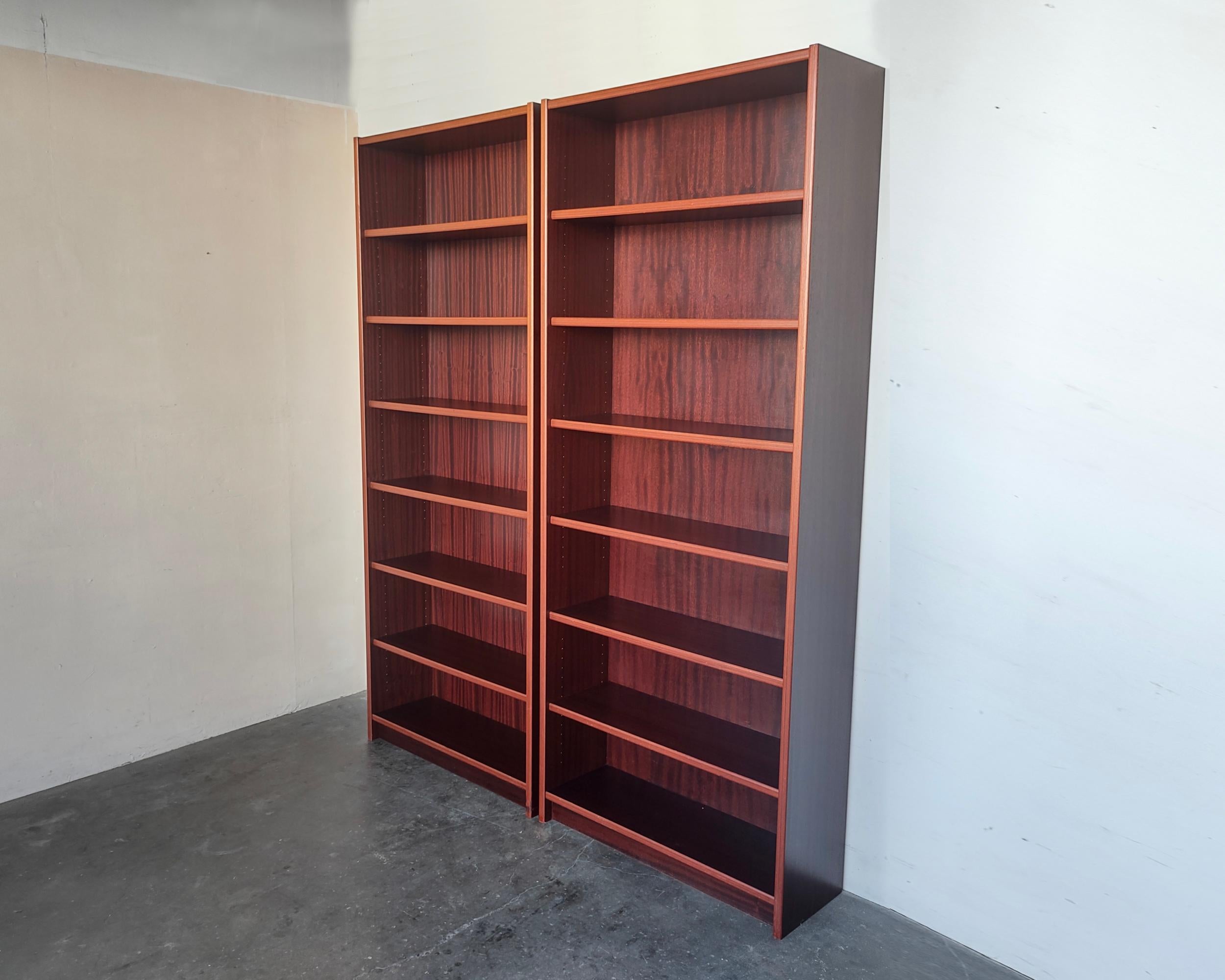 Set of two Danish modern rosewood bookshelves with six shelves on each. Adjustable shelves except one fixed in the center. Sun fading on interior surfaces and shelves, which would be made more apparent if the shelves are moved in different