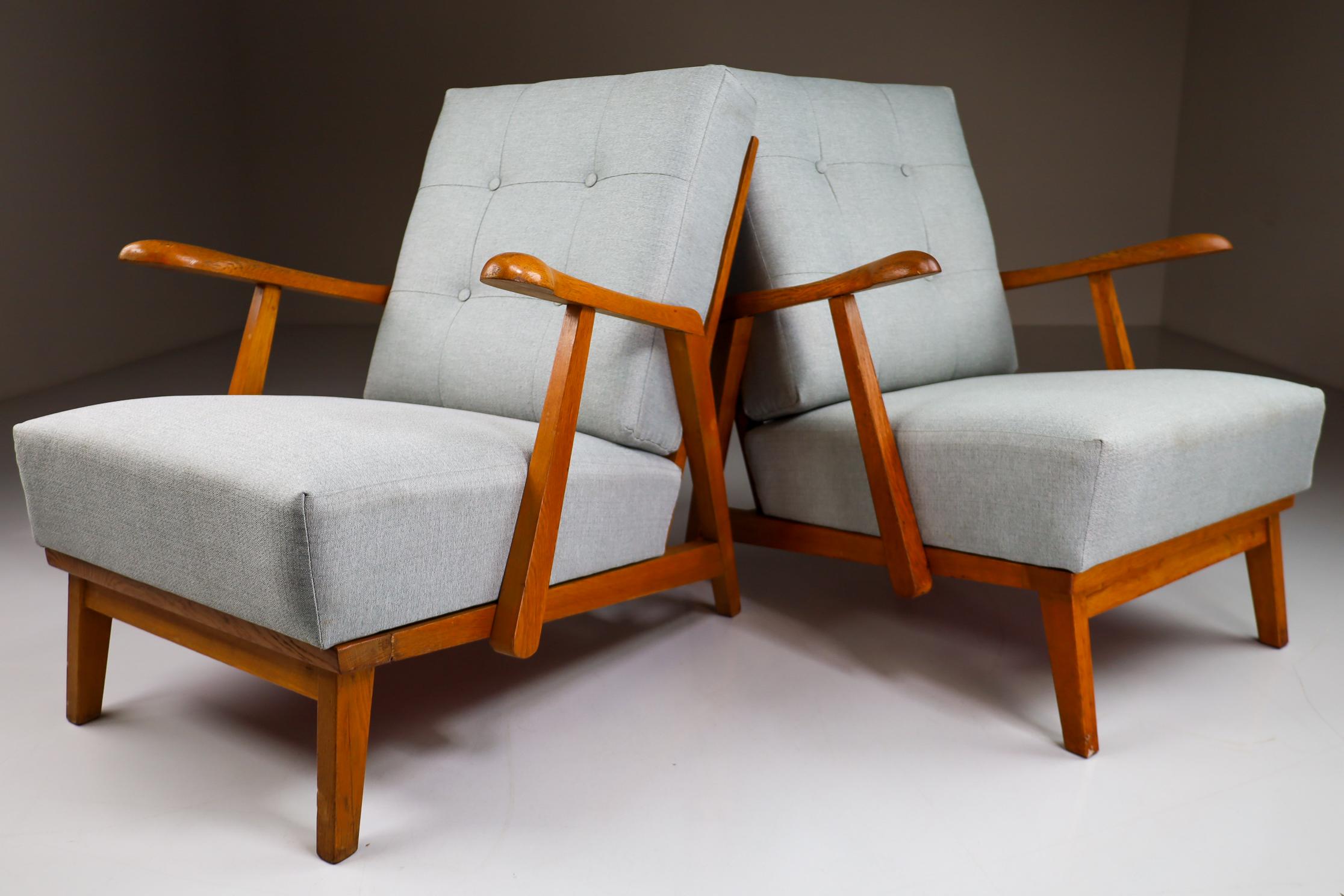 Pair of two original midcentury sculptural armchairs or lounge chairs manufactured and designed in France 1950s. Made of solid oak and professionally reupholstered in. These armchairs would make an eye-catching addition to any interior such as