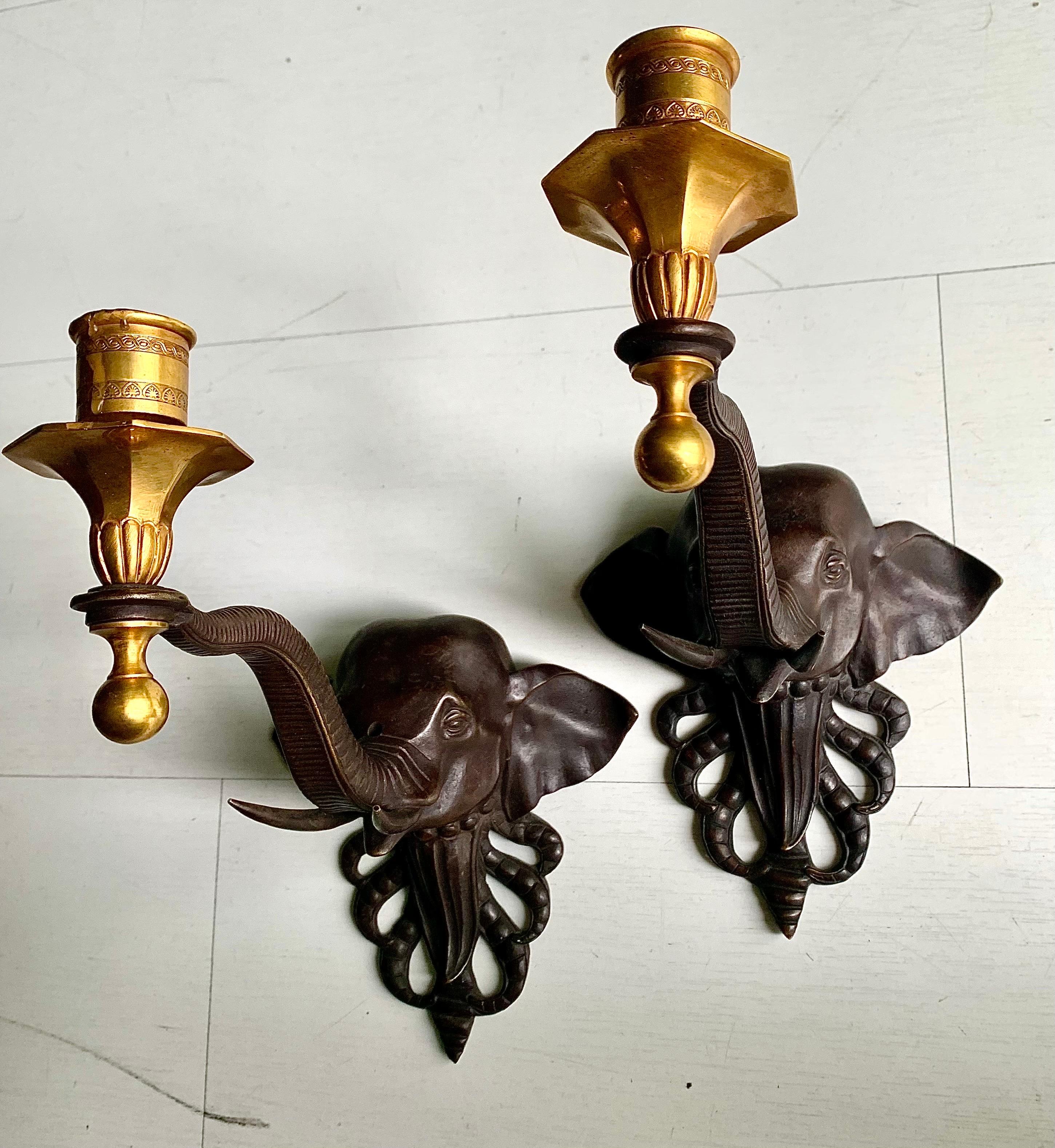 A pair of rare and original wall candle sconces, Regency style with influence of colonial fauna themes, the sconces represent a bronze elephant head, from whose trunk the ormolu bronze candle holder is held,