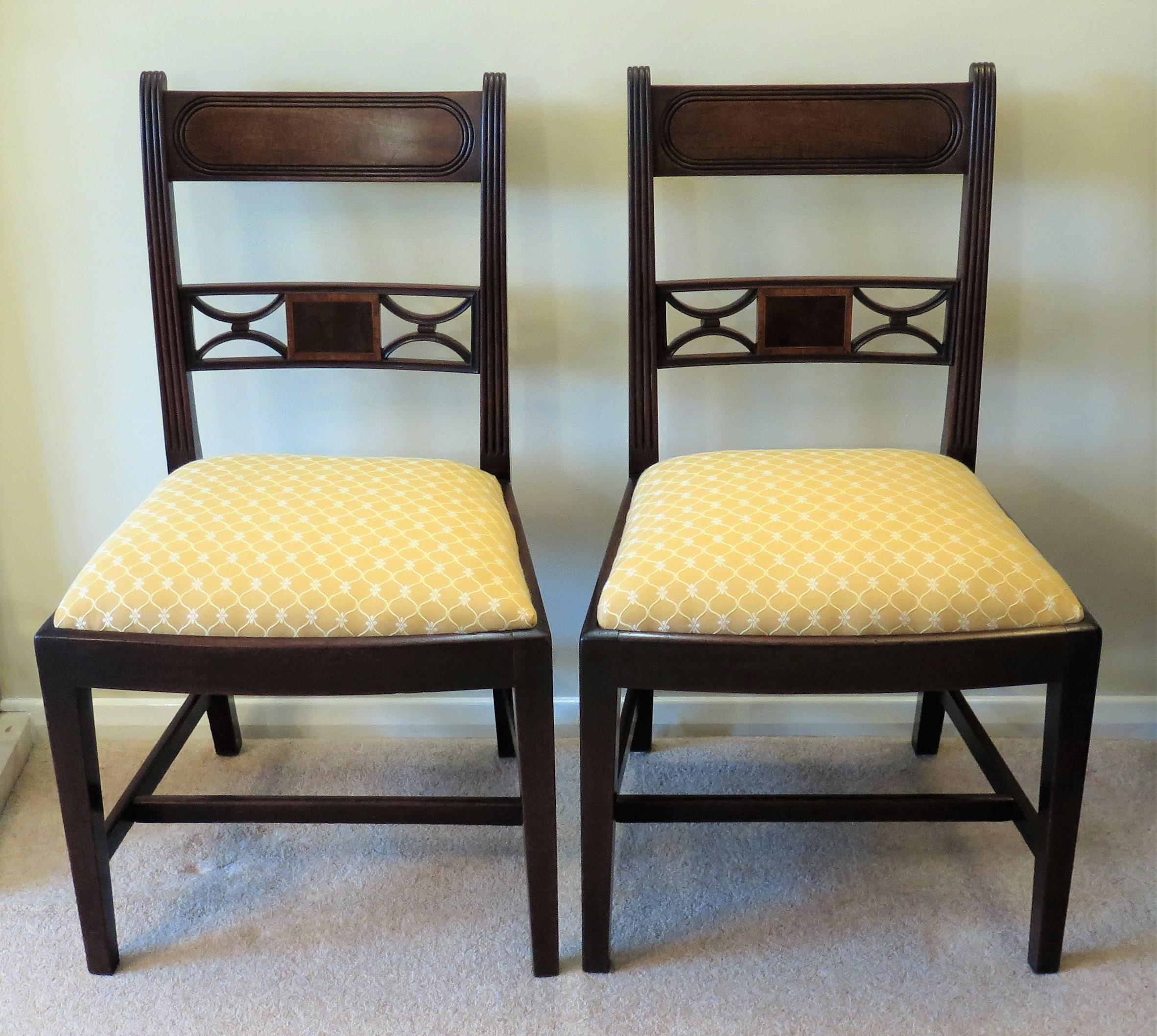 This a fine handmade pair of English, George 111rd, Sheraton period hardwood, possibly red walnut dining or side chairs with good carved detail and reupholstered drop in seats, dating to the late 18th century, circa 1790.

The chairs have many