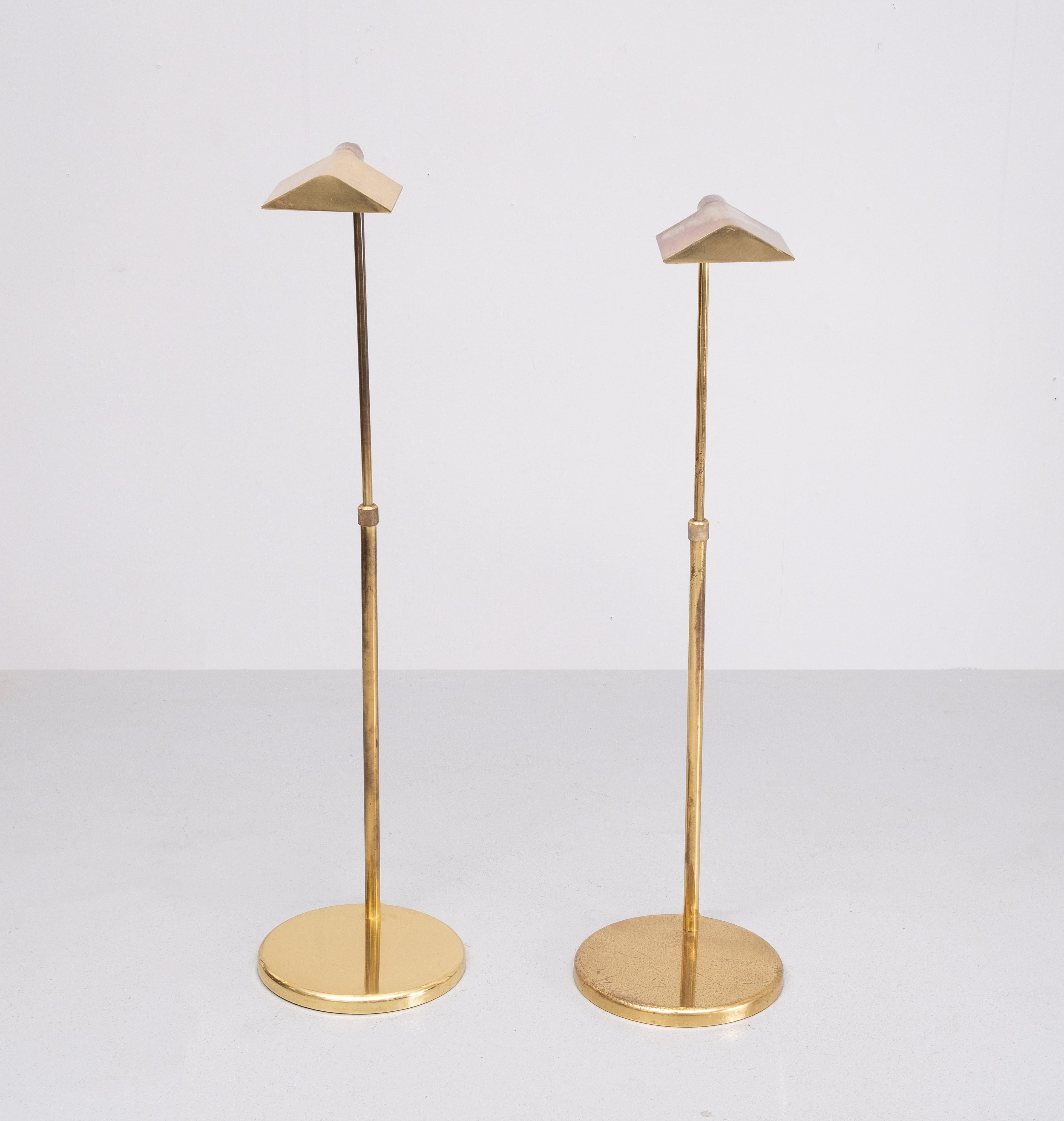Gorgeous pair of mid-century modern height adjustable pharmacy floor lamps featuring a solid Brass finish.  The light on and off switch with a Brass hardware knob. Beautifully crafted with a Brass  tightening ring in the center of the shaft to lock