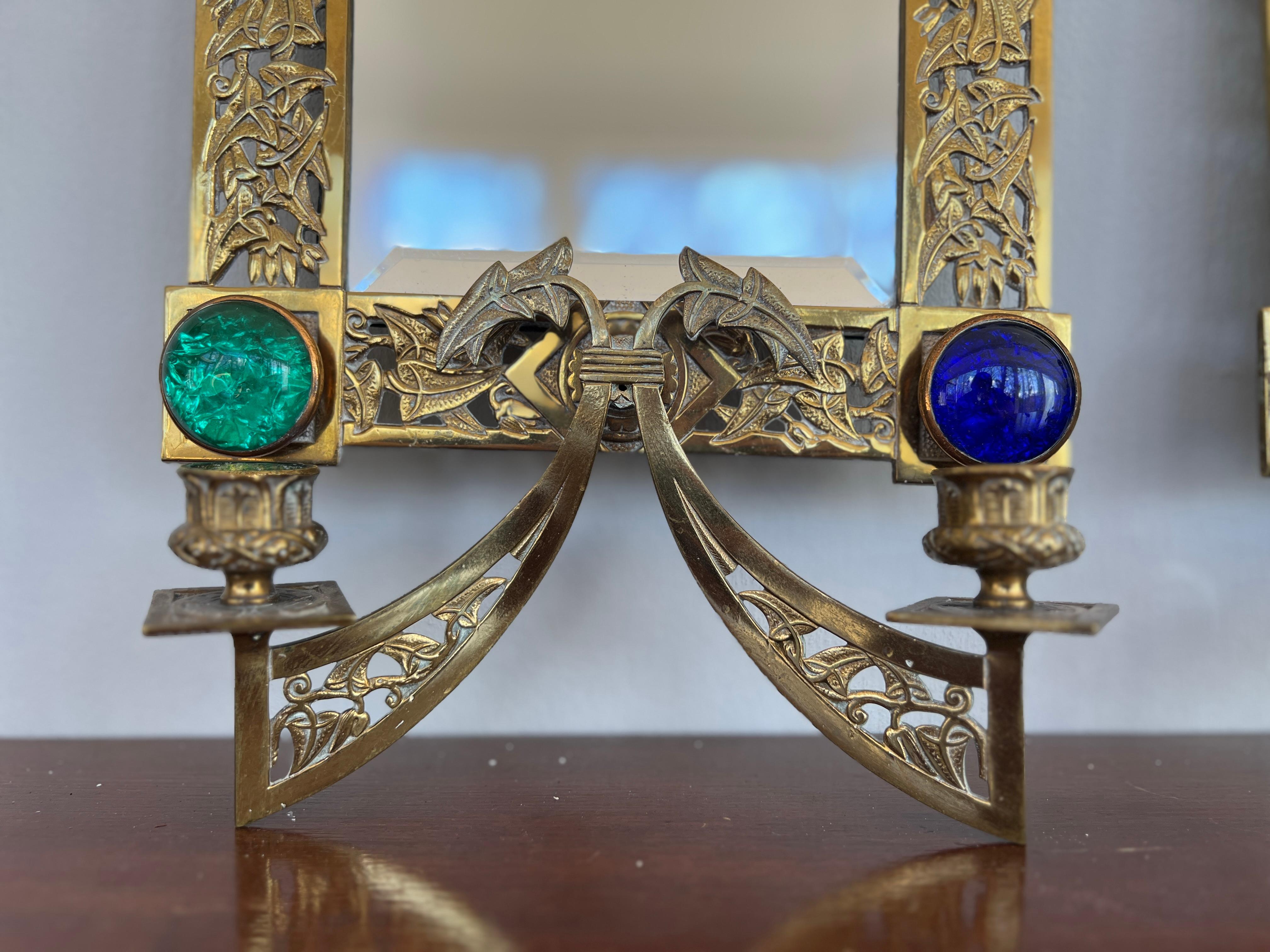 Likely English, circa 1890.

A pair of heavy and good quality bronze 2-light wall sconces. Each with a pierced surface showing arrays of floral, foliate and inset with 4 beautiful jeweled cabochons to each mirror. They both feature two-light dropped