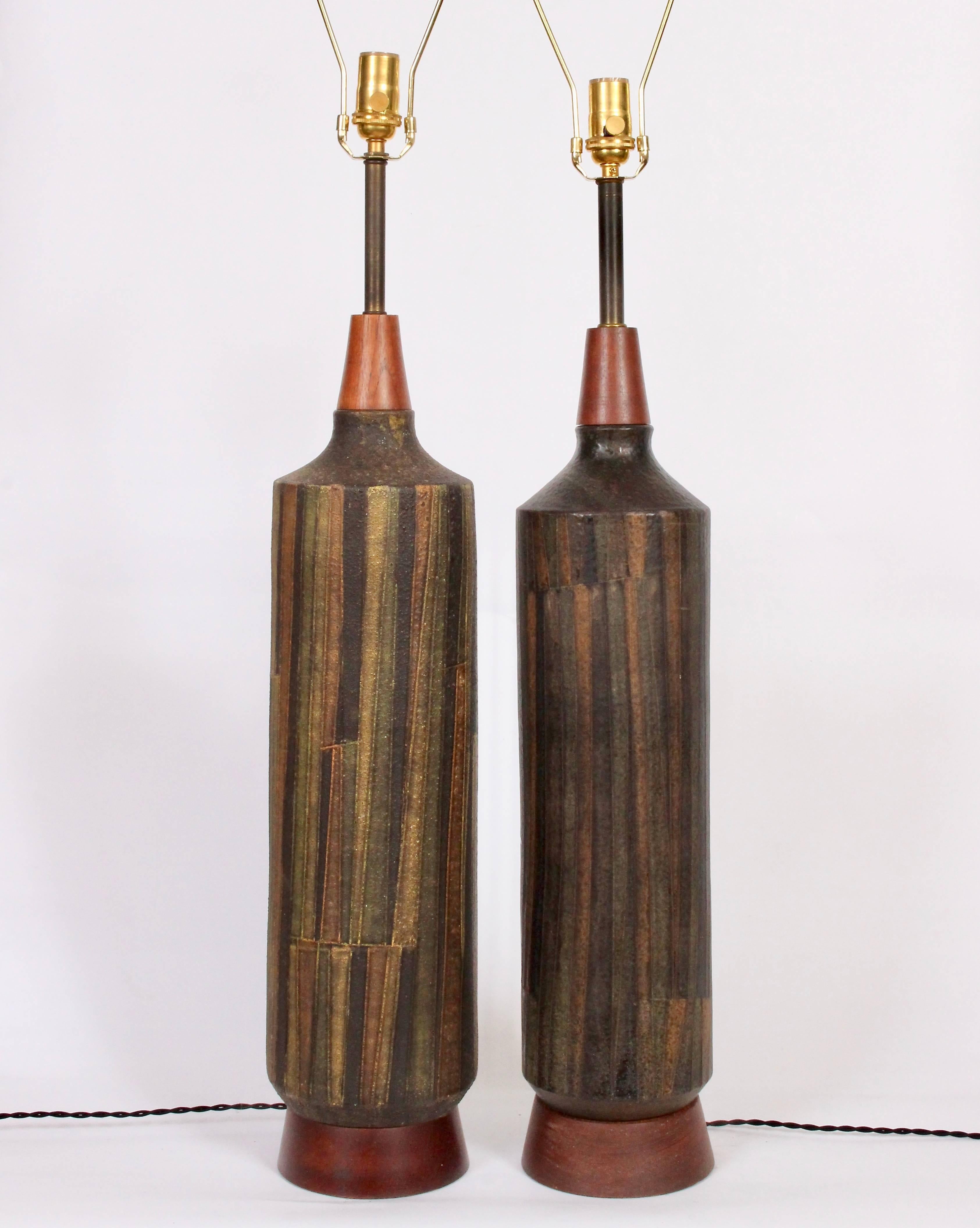 Two Milano Moderna Aldo Londi by Bitossi for Raymor Geometric Art Pottery Table Lamps. Small footprint. Featuring a cylindrical bottle form, conical teak detail, brass neck atop turned teak bases. With Milano Moderna knife cut relief and dark