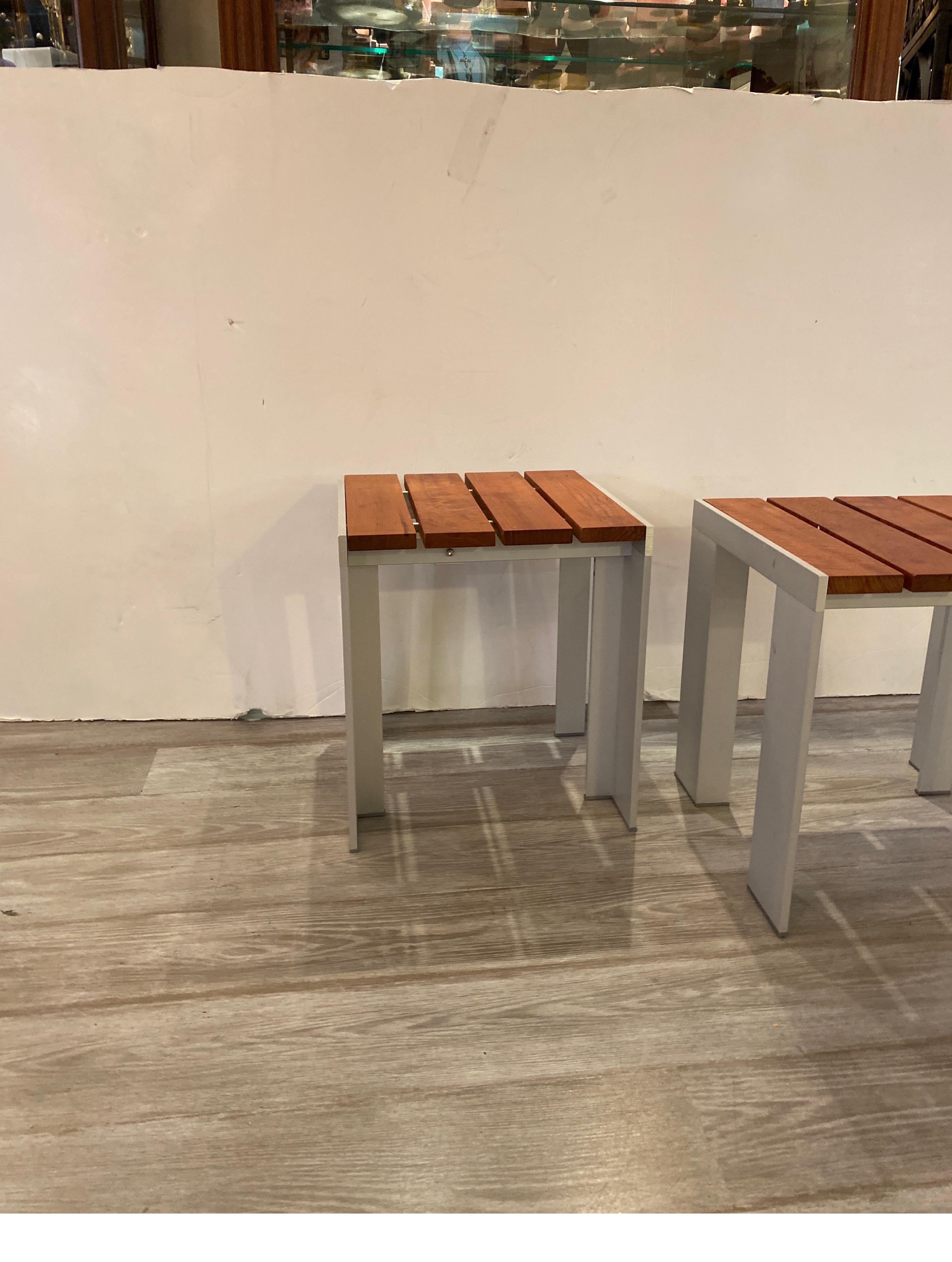 Chic Post Modern pair of aluminum and teak slated benches. these are also usable as bunching tables or side tables. Made in Spain by Deneb Stua 16 by 16 by 17.5.