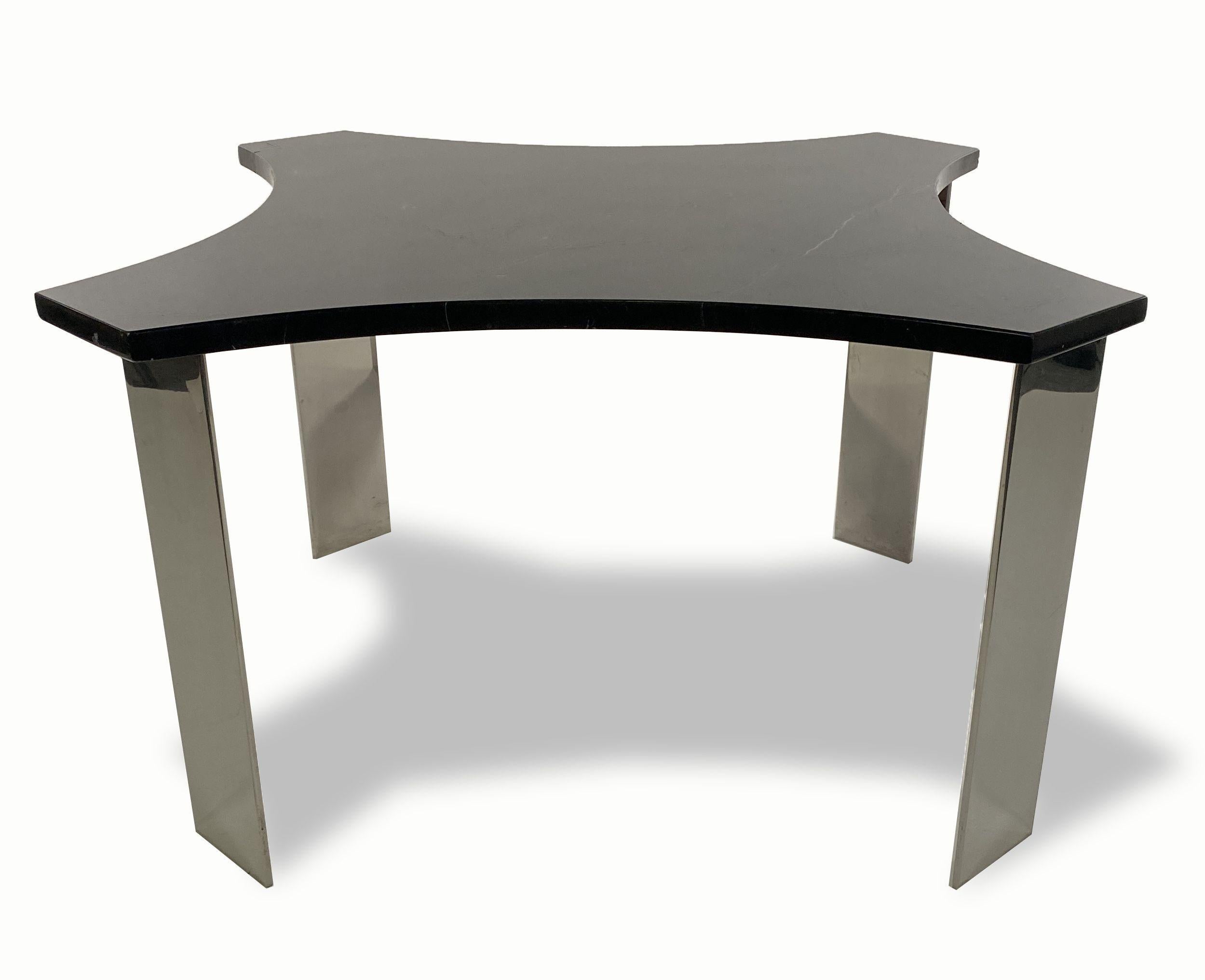 The stylized star shaped black granite top above a framework supporting polished steel rectangular legs.