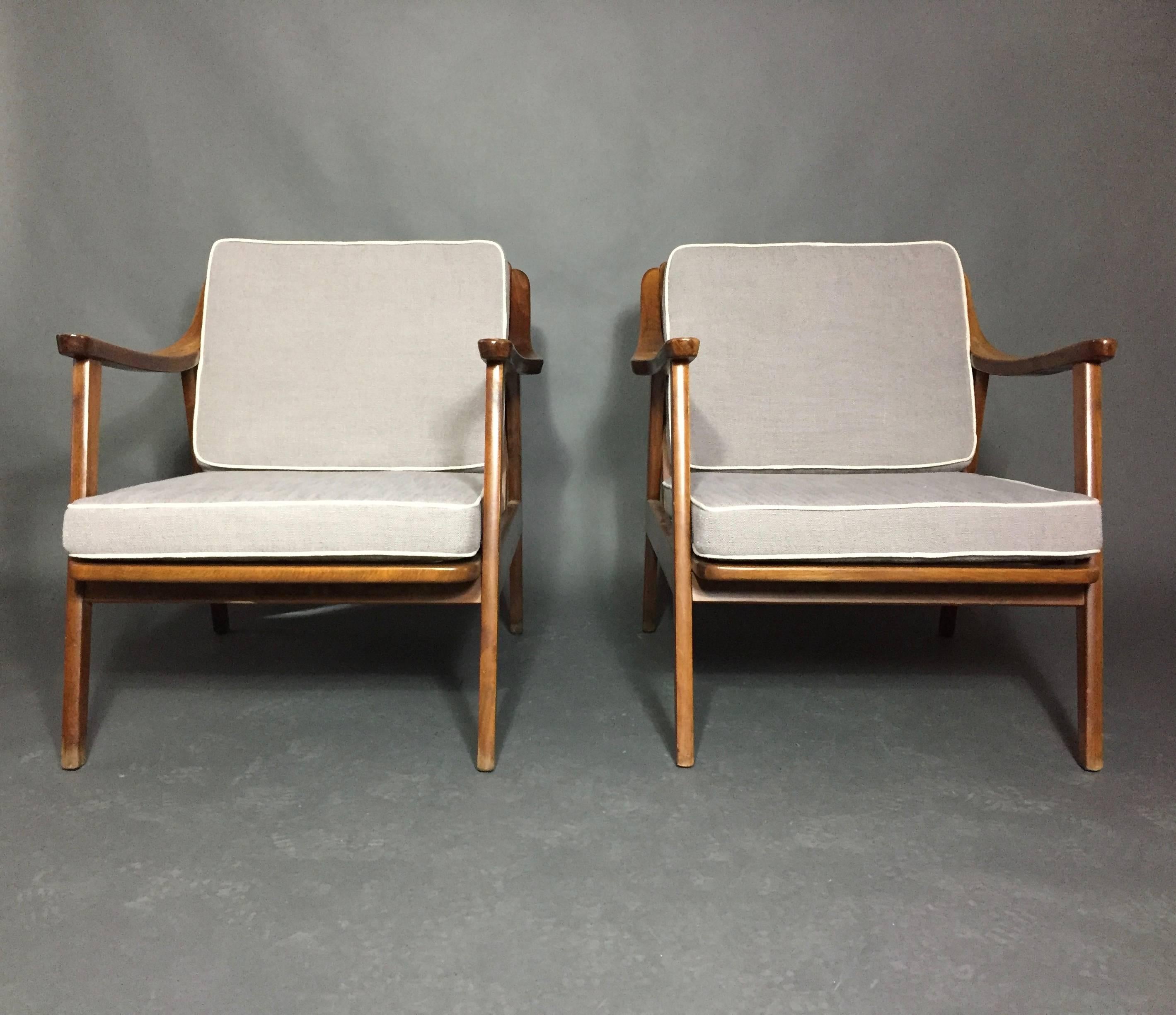 Well proportioned and nicely shaped pair of American Modern lounge chairs from the 1960s with open and angled slat backs. We left the wood in vintage condition as we love the patina of the chairs frames against the new light grey upholstered covers