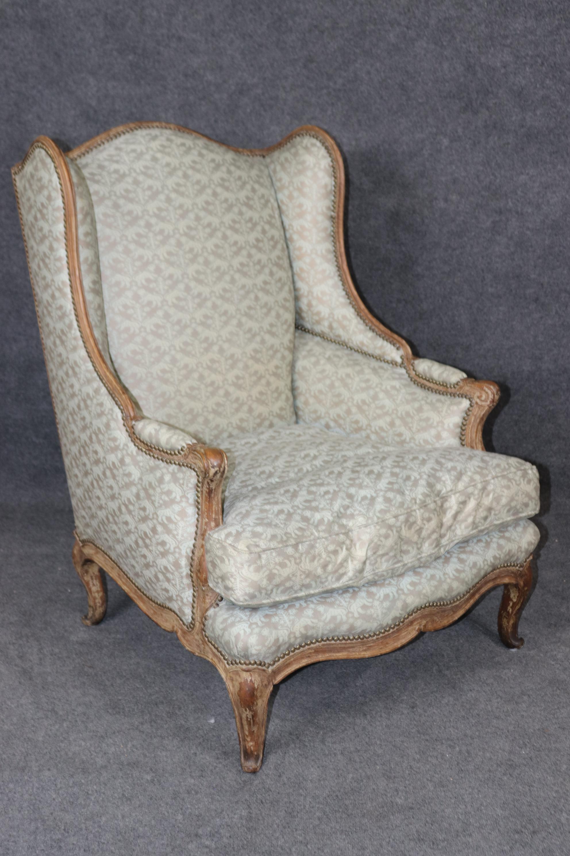 This is a superb pair of time-worn distressed paint decorated pair of wingchairs. The chairs feature gorgeous lines and very sophisticated design and upholstery. The finish is fantastic and is completely original. They were made in France and date