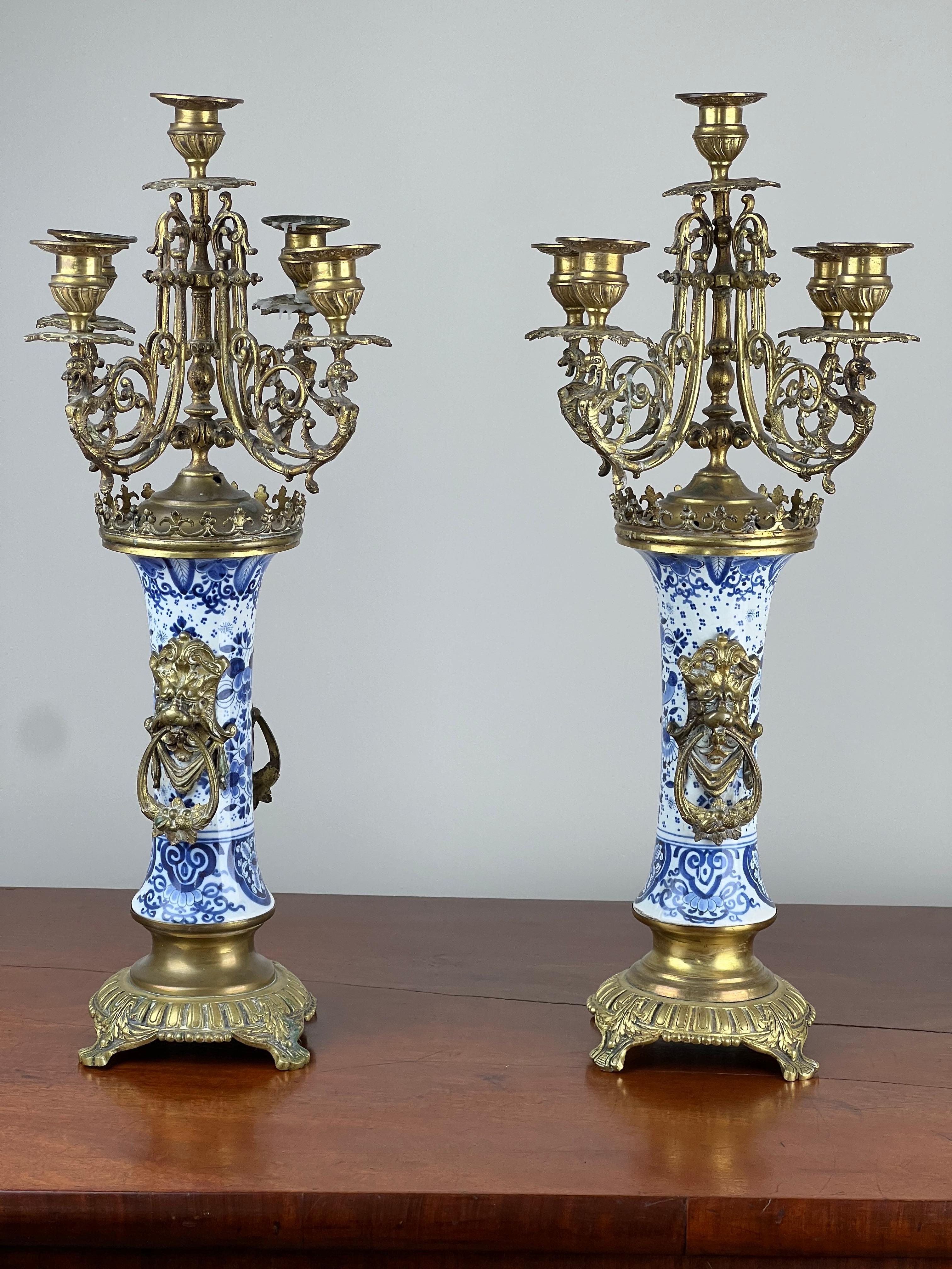 Questa straordinaria coppia di candelabri a cinque luci del XIX secolo combina l'arte senza tempo della porcellana olandese blu e bianca di Delft con l'eleganza delle montature in bronzo dorato. Ogni fusto colonnare è finemente decorato nella