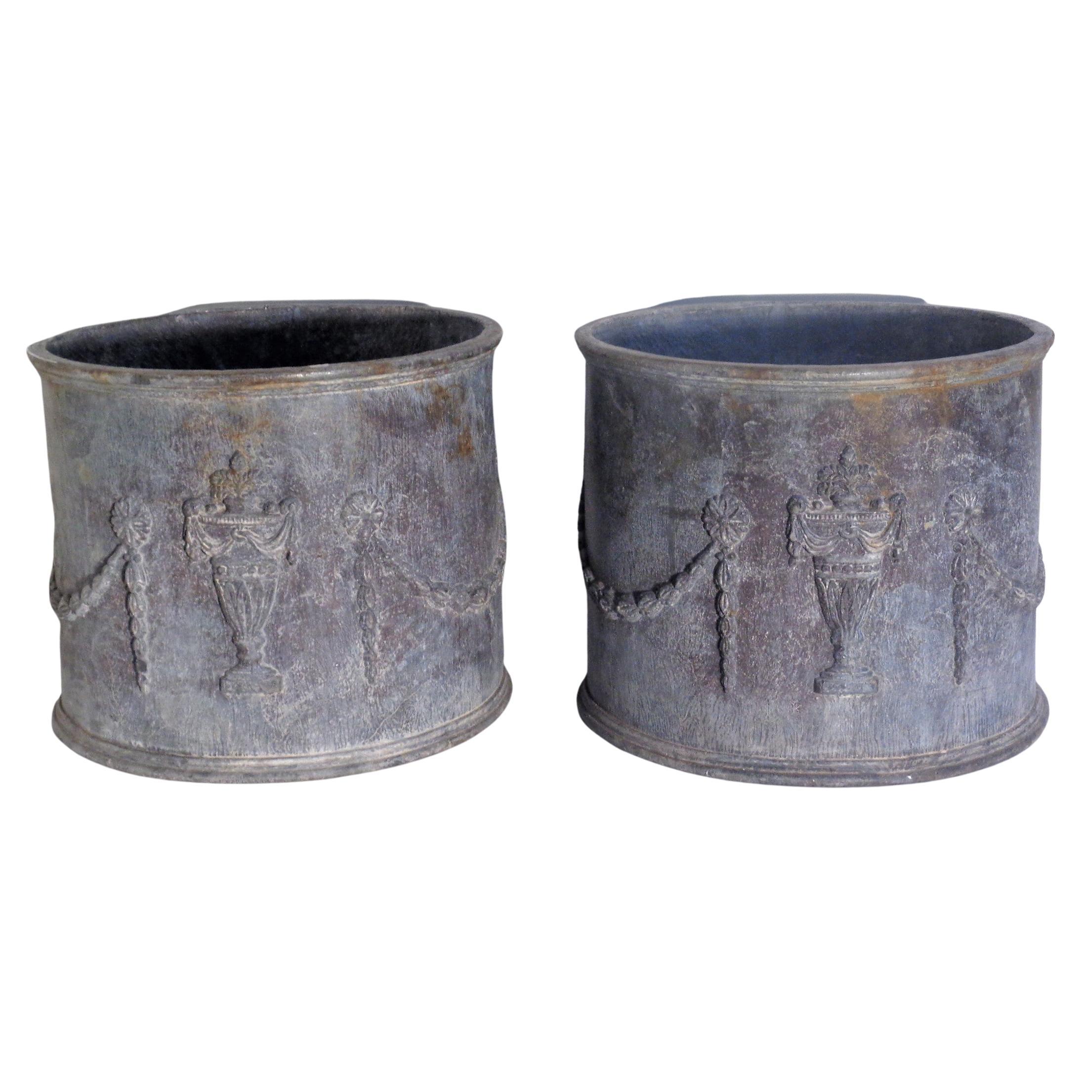 Pair of antique Neoclassical Adams style circular lead garden planters with urn and swag relief decoration / drainage holes at bottom. Overall nicely aged old surface color. Measure 10